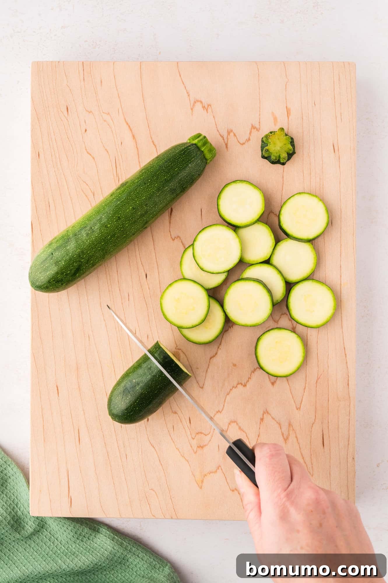 Zucchini being expertly sliced into uniform rounds with a sharp knife.