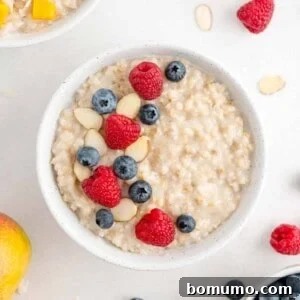 Crockpot oatmeal topped with raspberries, blueberries, and almonds, presented in a clean white bowl.