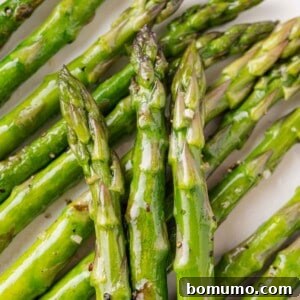 Sautéed asparagus spears, perfectly cooked and layered on a plate, ready to be served.