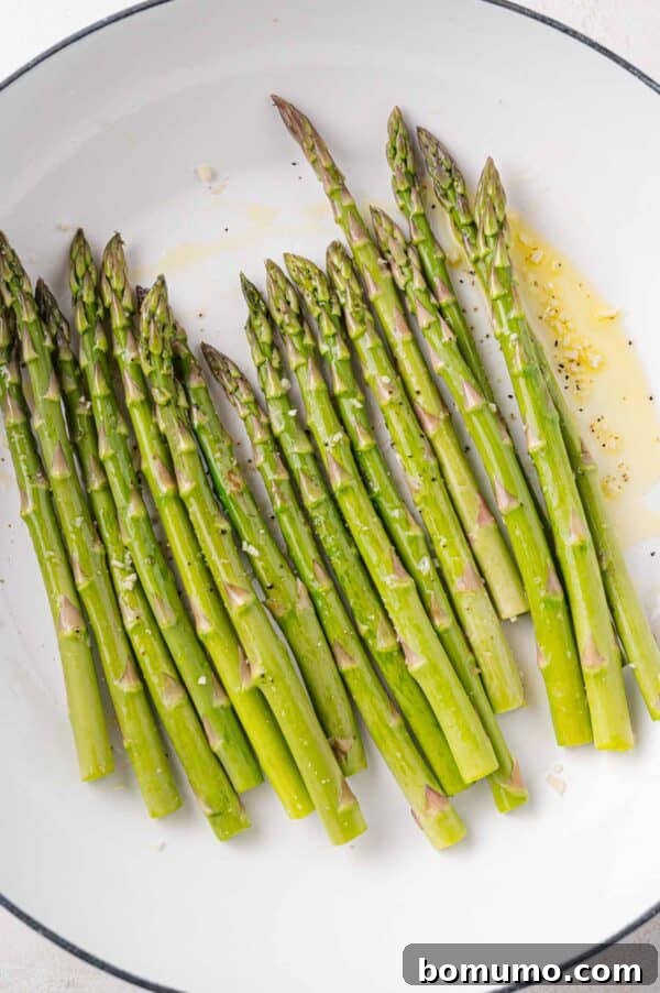 Trimmed asparagus spears added to a hot skillet, ready for sautéing.