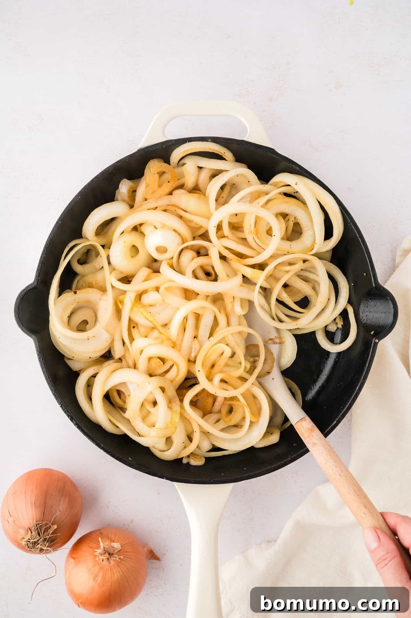 Onions partially sautéed, showing translucency and light browning, progressing through the cooking process.
