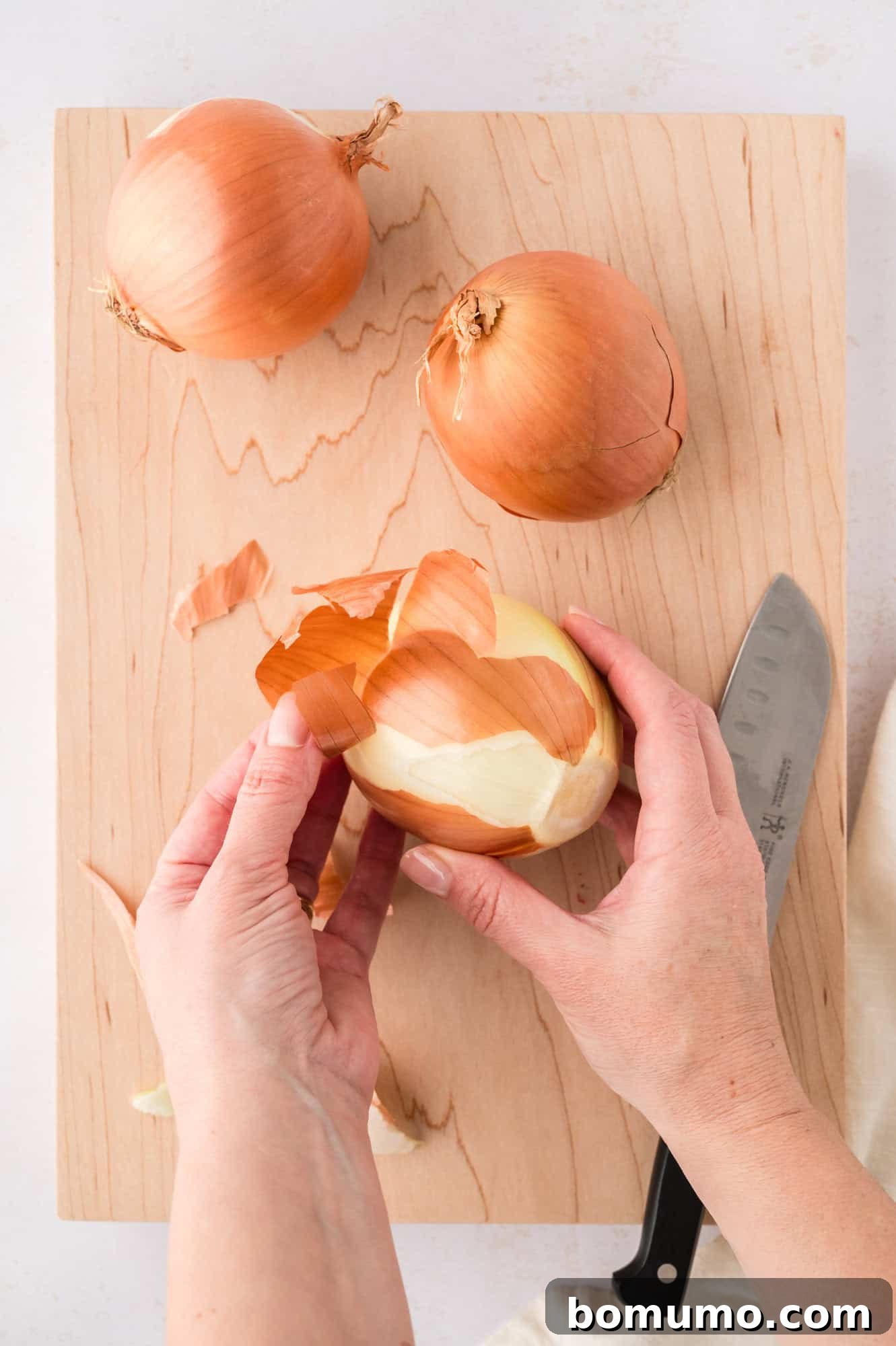 Close-up shot of an onion being peeled, revealing its layers, a crucial first step in preparing sautéed onions.