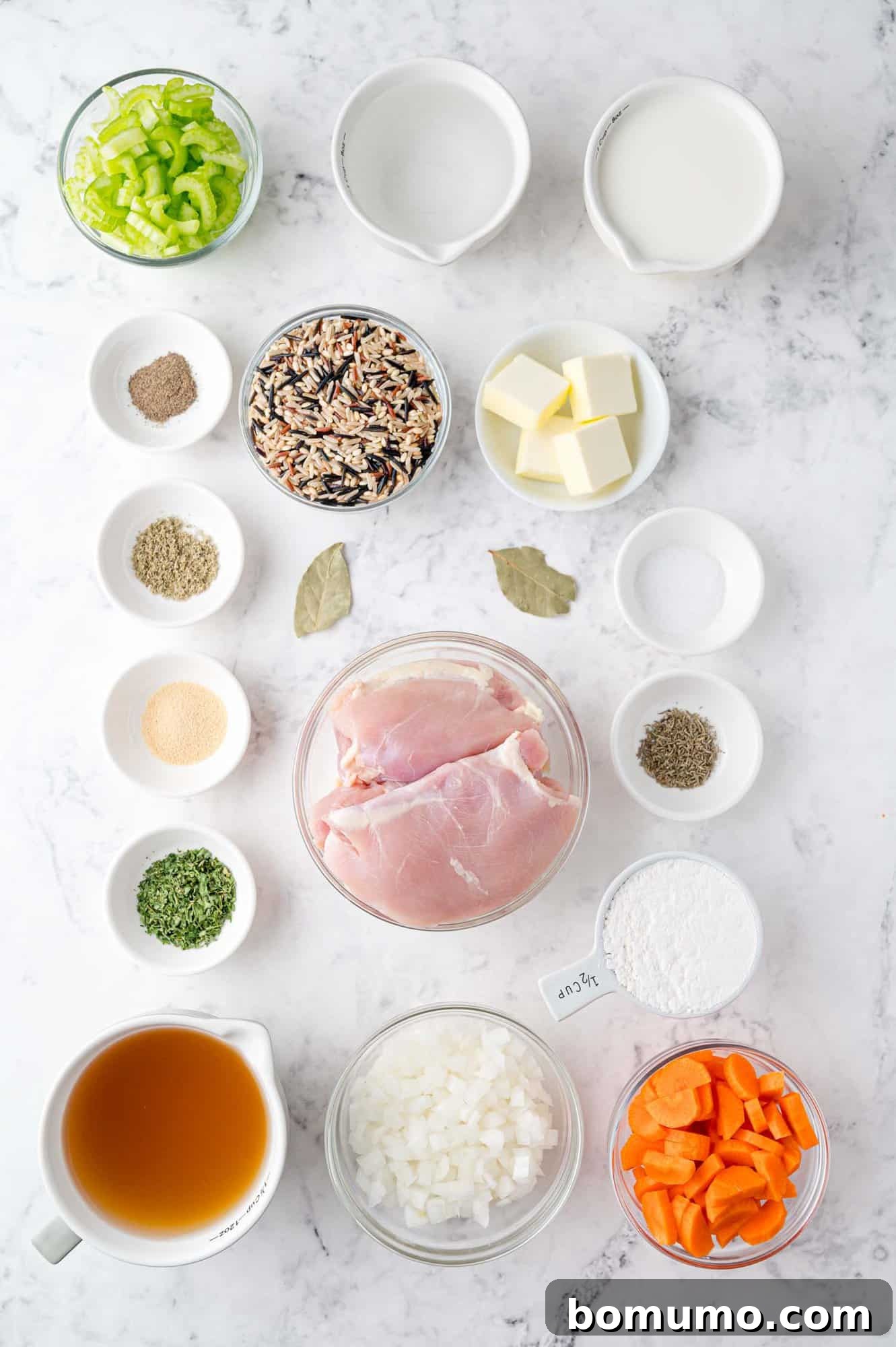 An array of fresh ingredients for crockpot chicken wild rice soup, including chicken, vegetables, and spices, neatly laid out on a countertop before preparation.