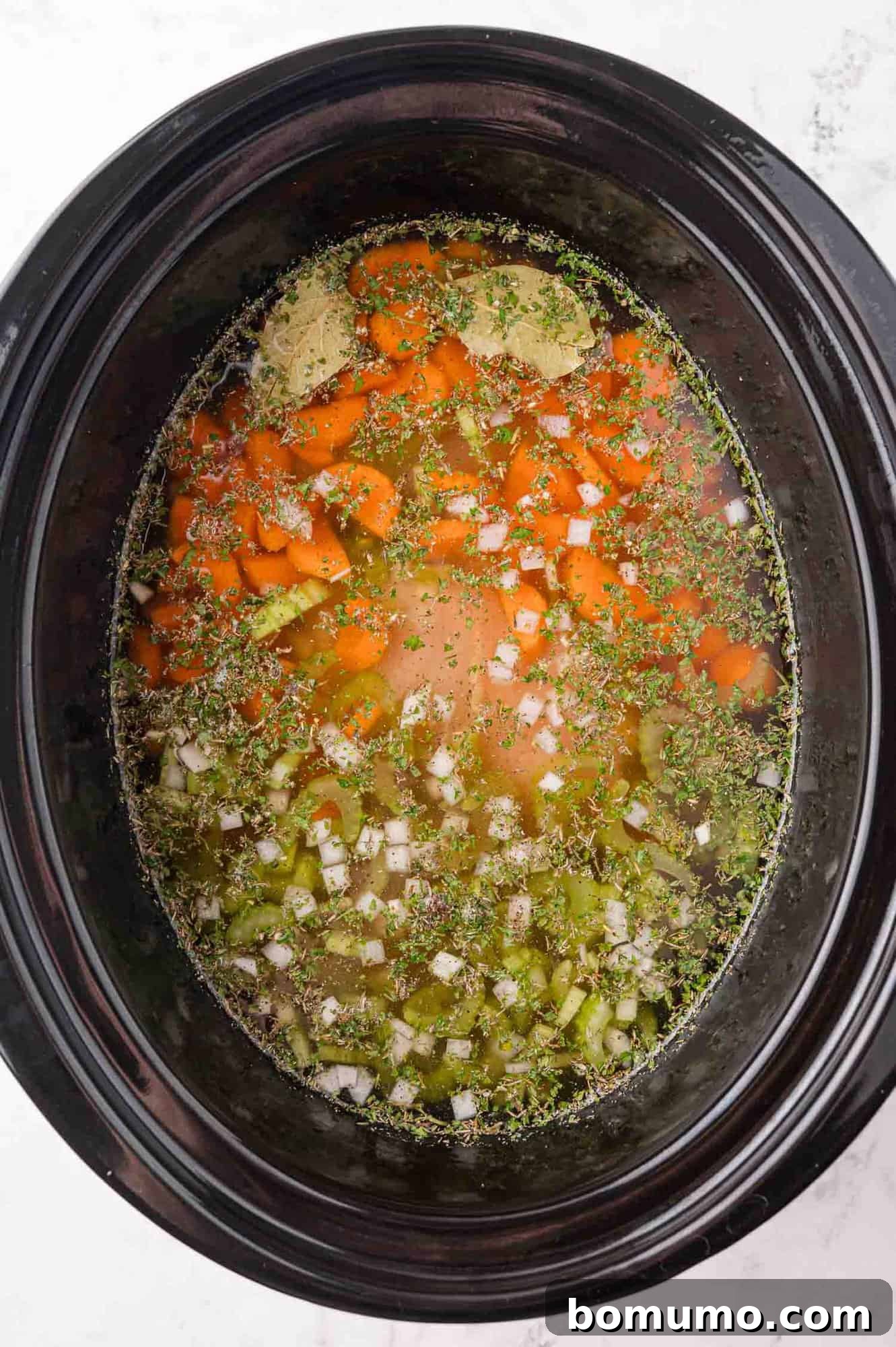 All the initial ingredients for crockpot chicken wild rice soup mixed together inside a slow cooker pot, ready for cooking.