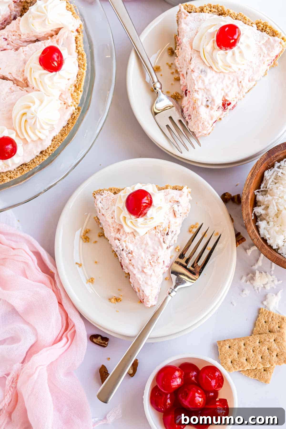 Golden Treasure Pie 3 An overhead shot of a single slice of Millionaire Pie resting on a white plate, elegantly adorned with a dollop of whipped cream and a bright maraschino cherry on top, highlighting its inviting and fluffy texture.