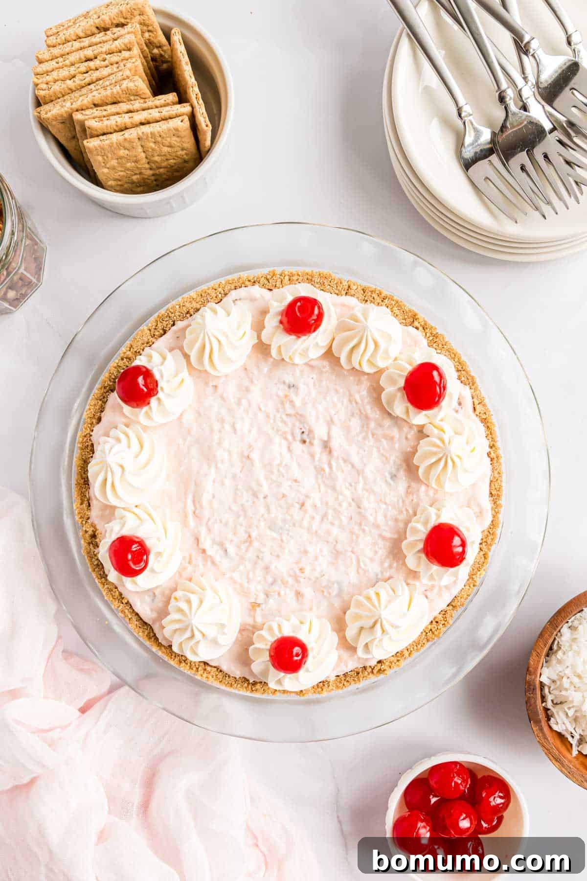 Golden Treasure Pie 10 A stunning Millionaire Pie, now complete with generous swirls of whipped cream and a scattering of bright maraschino cherries, showcasing its final, delectable presentation.