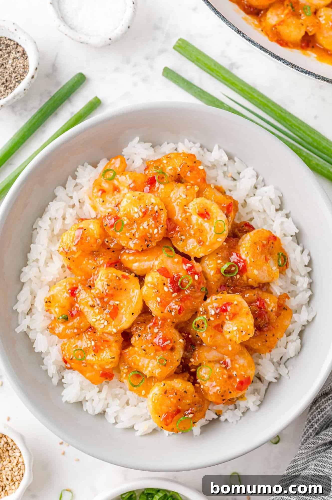 Close-up of succulent Firecracker Shrimp in a glossy, spicy red-orange sauce, beautifully arranged on a bed of white rice, demonstrating its vibrant appeal as a main dish.