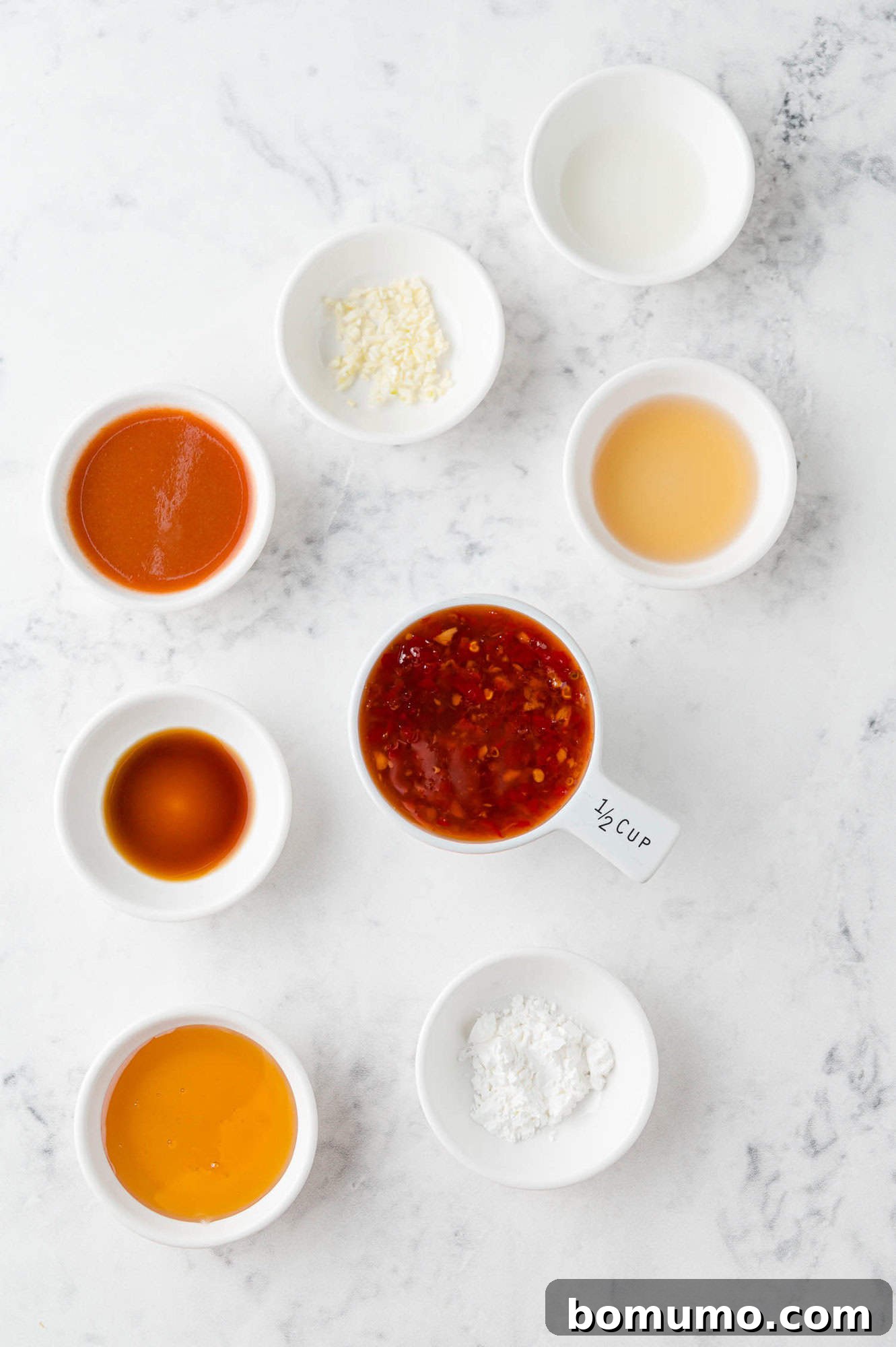 Individual ingredients for the Firecracker Shrimp sauce laid out on a clean surface, including sweet chili sauce, sriracha, honey, and garlic.