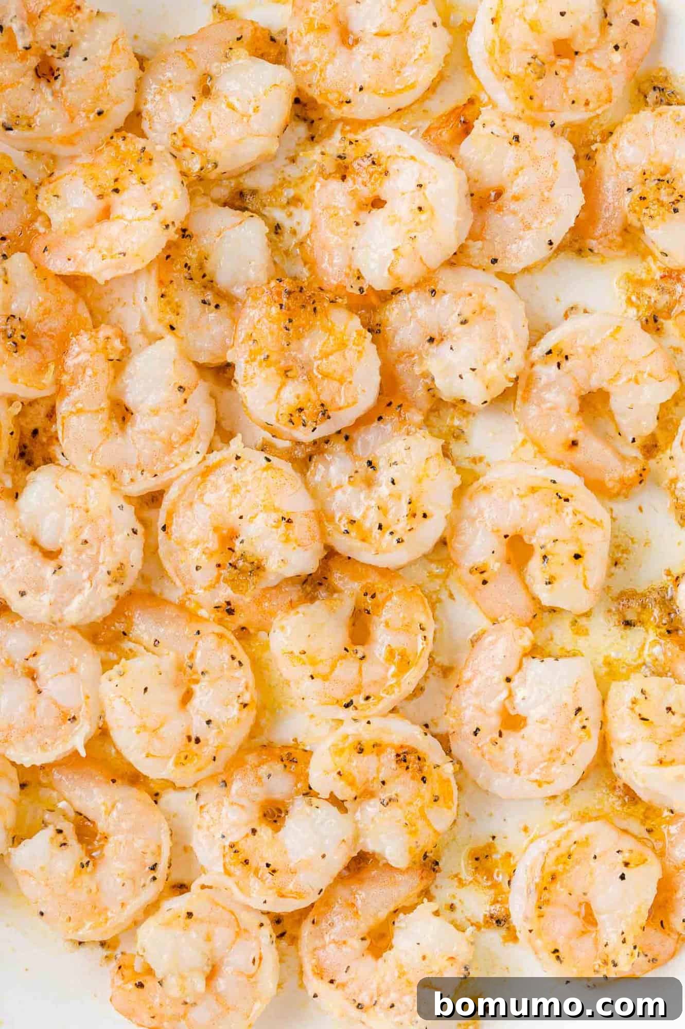 Perfectly cooked, pink shrimp arranged in a single layer in a hot skillet, just before the Firecracker sauce is added.
