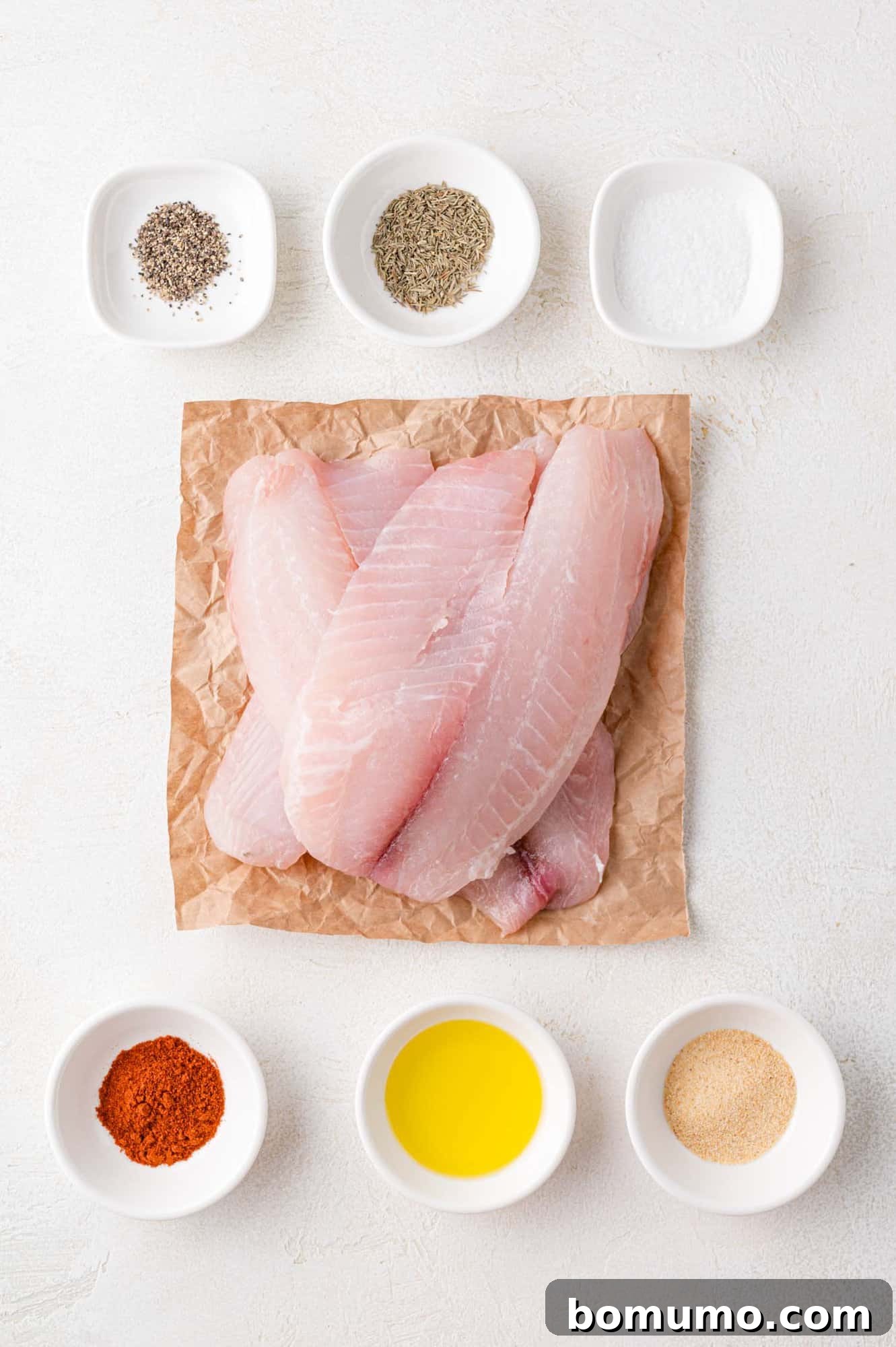 An overhead view showcasing all the fresh ingredients required for preparing delicious air fryer tilapia, neatly arranged on a kitchen counter.