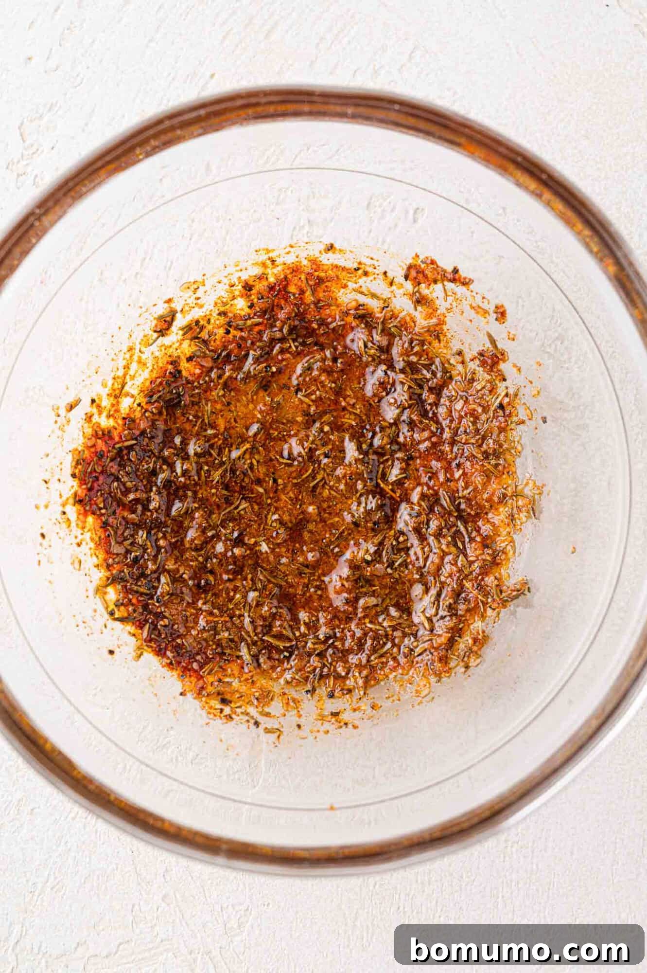 A small bowl containing the perfectly blended seasoning mixture for tilapia, glistening with olive oil and vibrant spices.