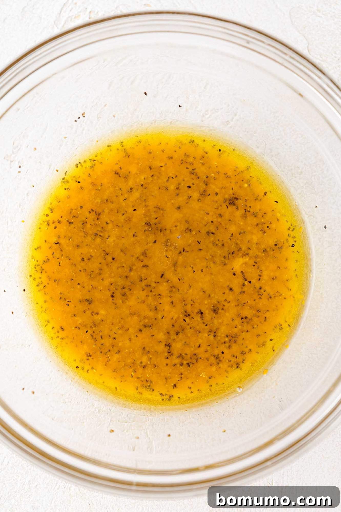 The vibrant salad dressing, perfectly mixed and emulsified, resting in a clear glass bowl, ready to be drizzled.