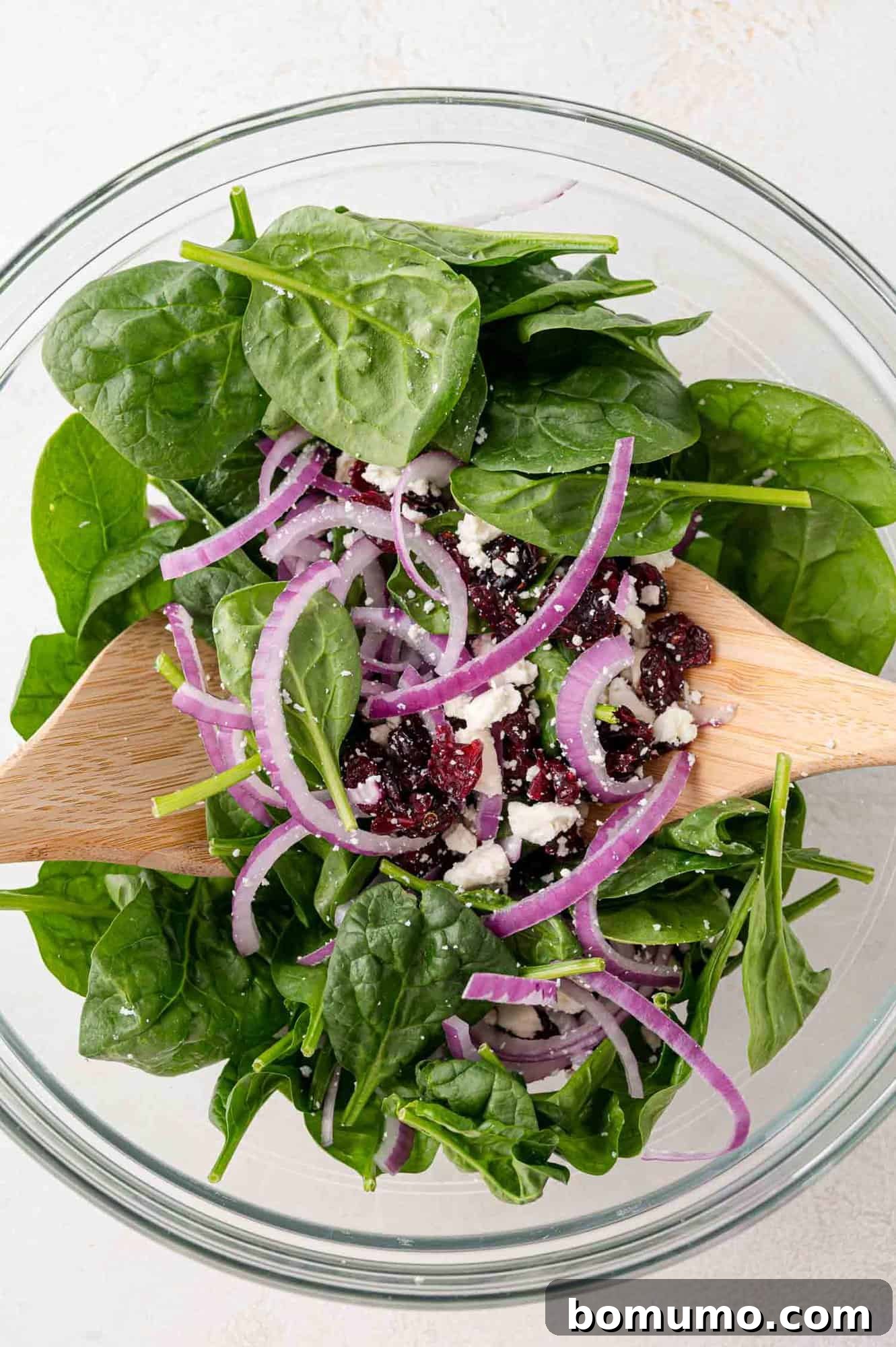 A fresh salad being tossed gently in a large mixing bowl, before the final additions of juicy oranges and crunchy almonds.