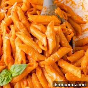 Vodka pasta on penne sauce, garnished with fresh basil leaves.