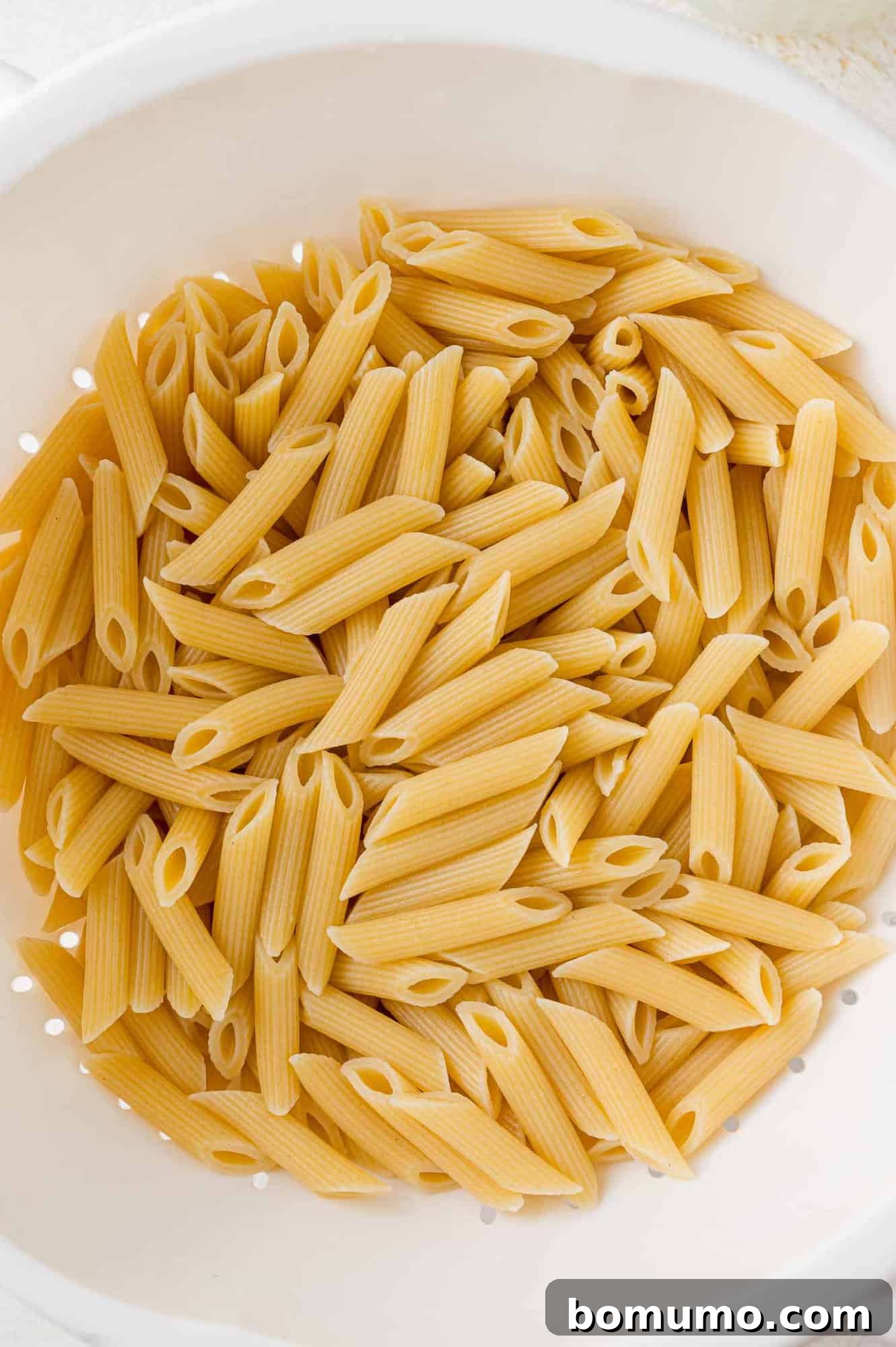 Penne pasta draining in a colander. 