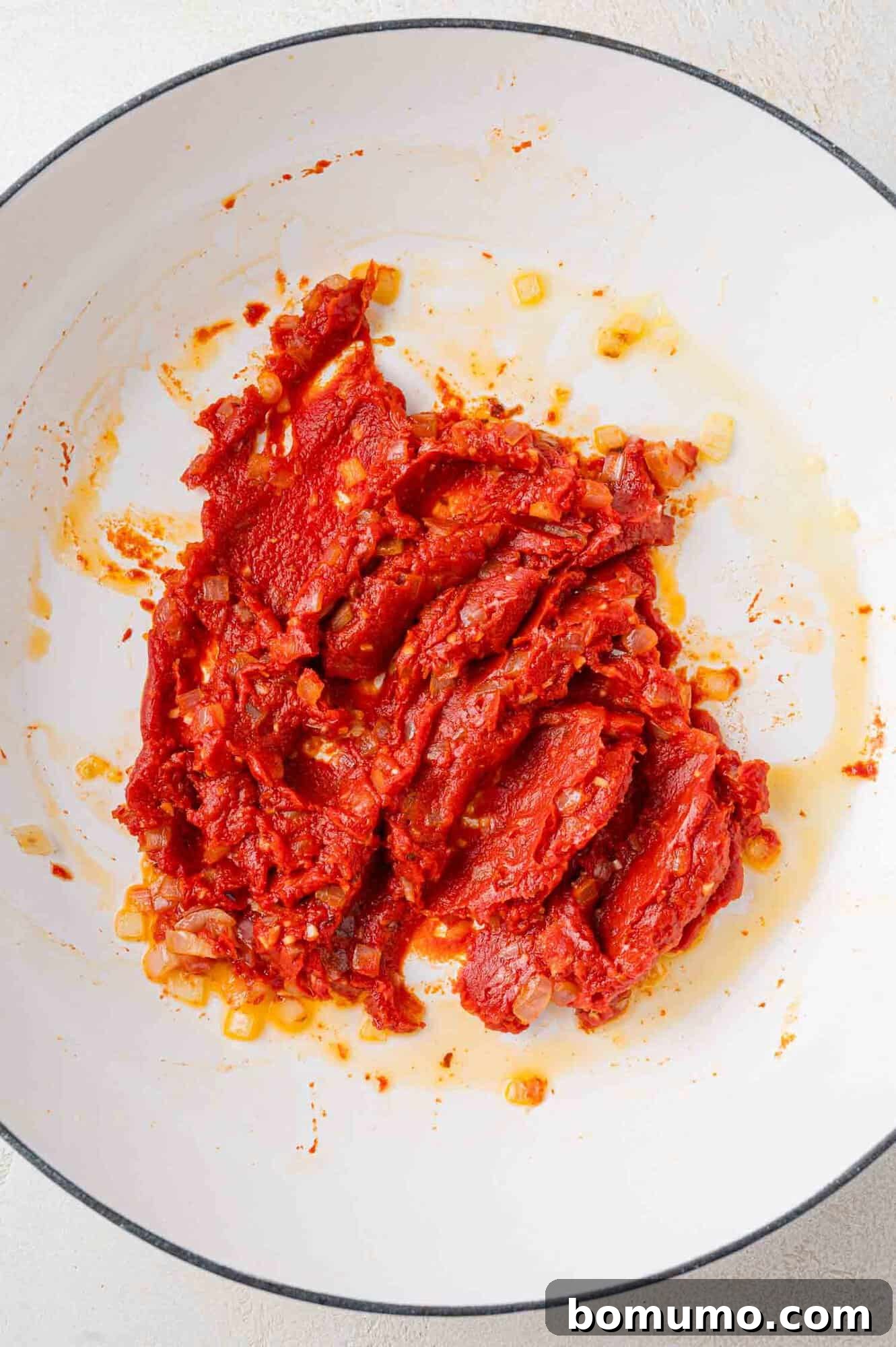 Tomato paste added to sautéed onions and garlic.
