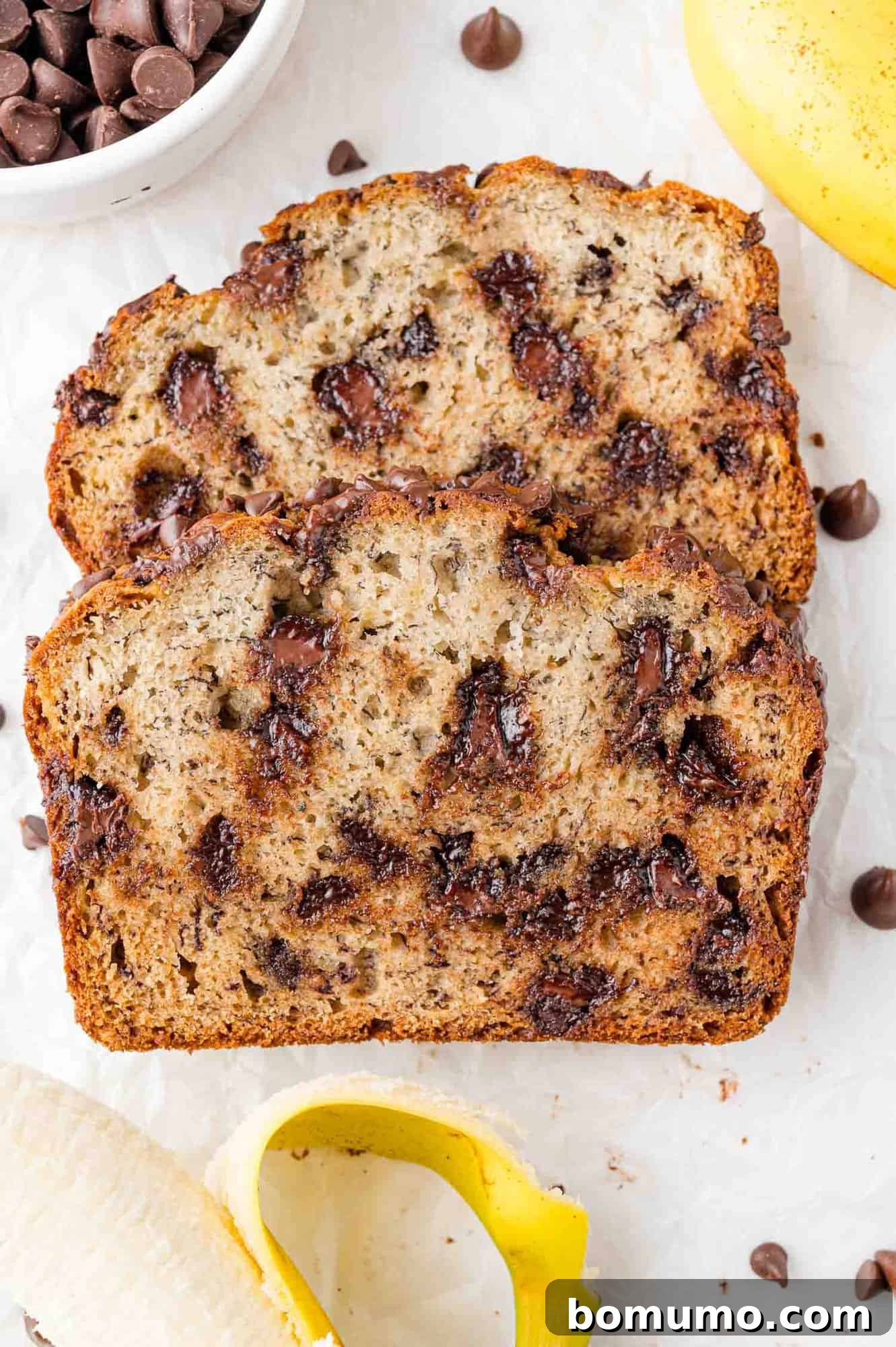 Two enticing slices of chocolate chip banana bread, slightly overlapping, showcasing golden brown crust and melty chocolate chips.