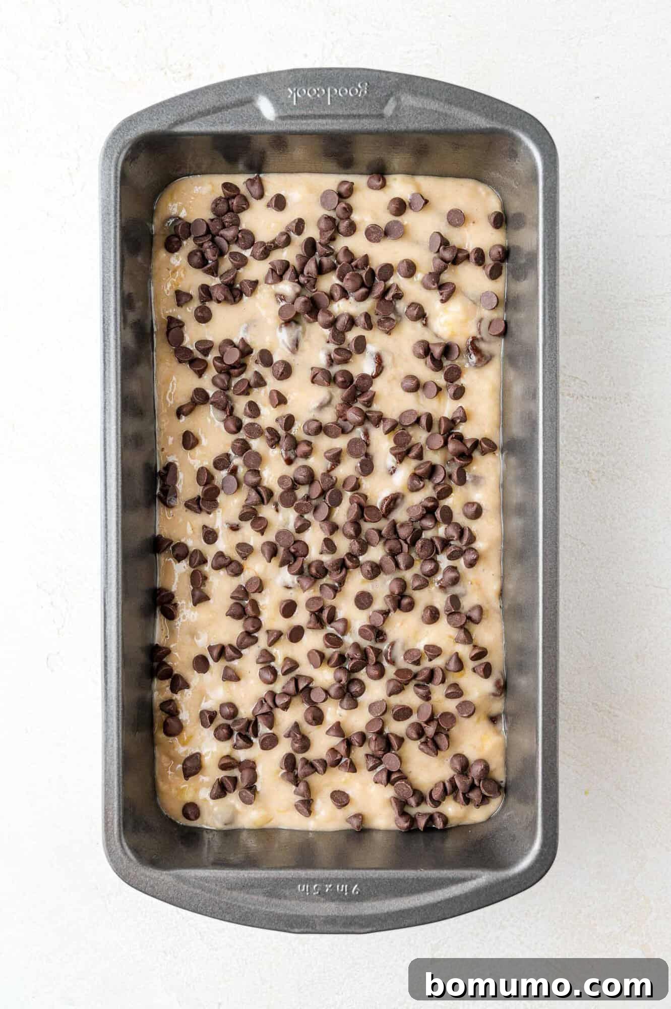 Unbaked banana bread batter in a loaf pan, generously topped with mini chocolate chips.