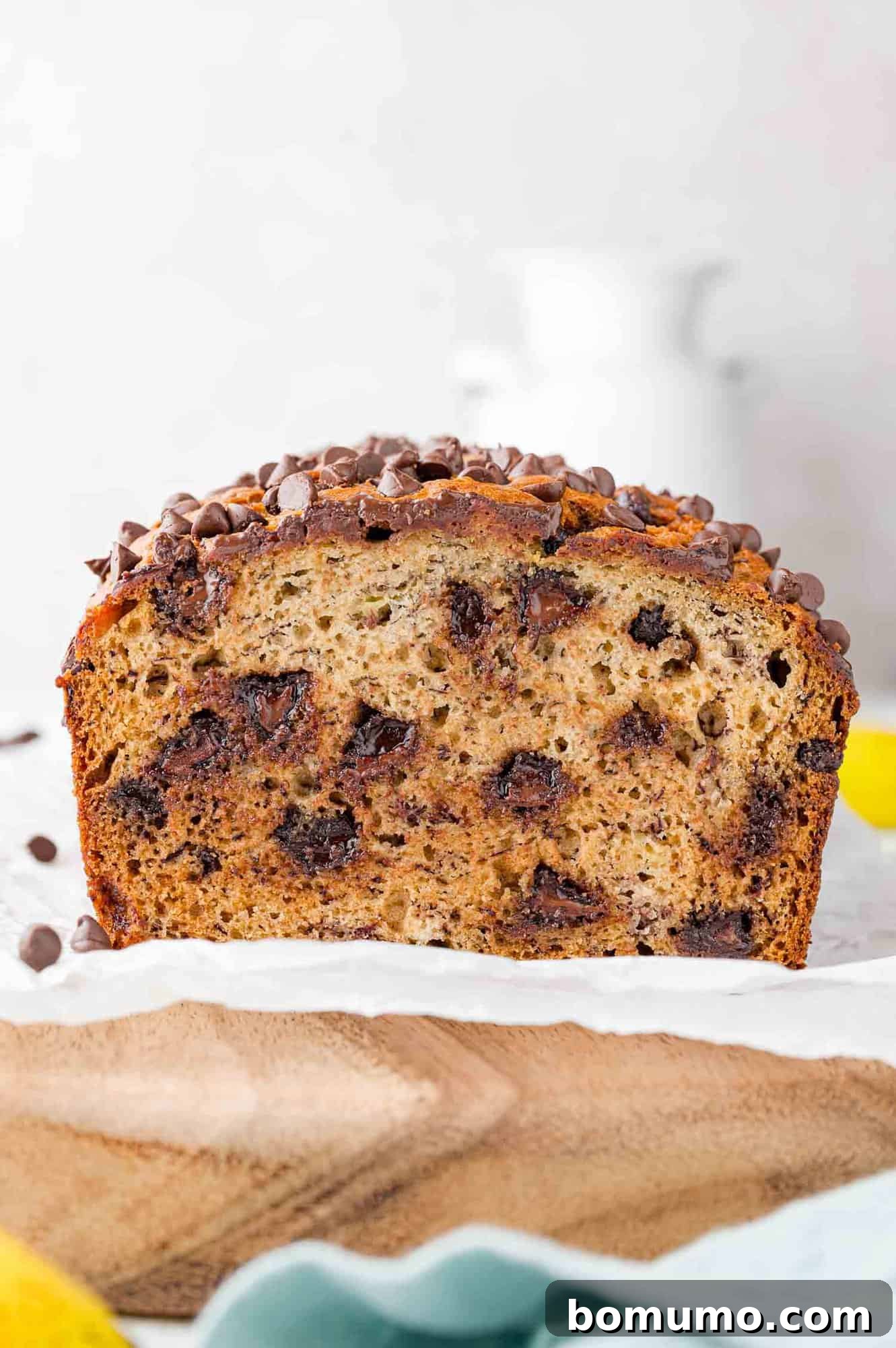 A beautifully baked loaf of chocolate chip banana bread, partially sliced, revealing its moist interior and generous chocolate chips.