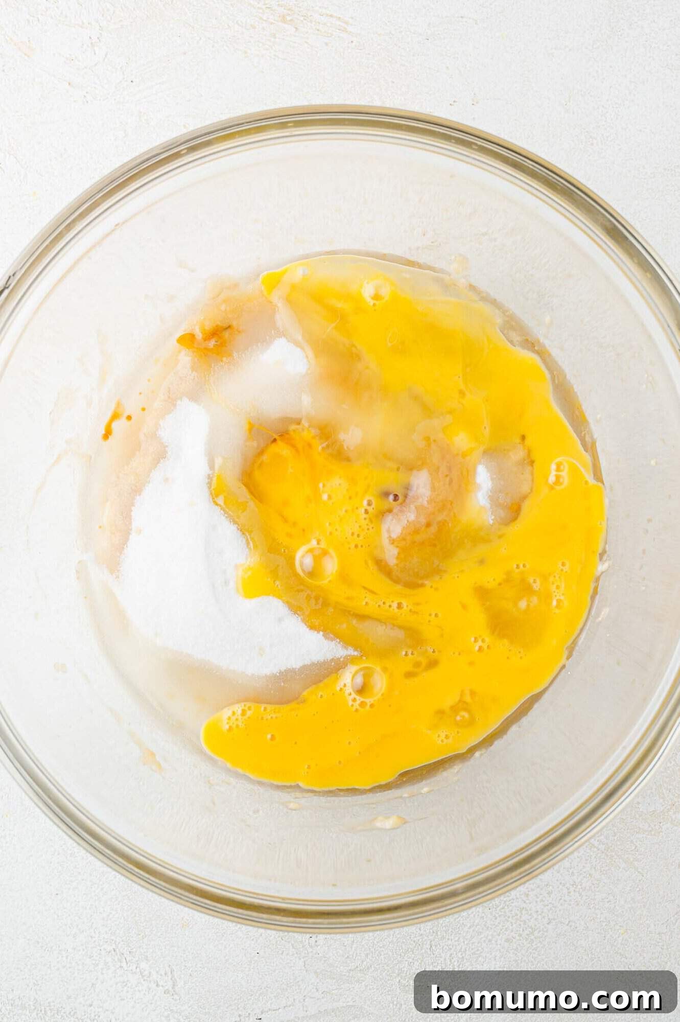 All wet ingredients, including mashed bananas, eggs, oil, sugar, and vanilla, in a clear glass bowl before mixing.