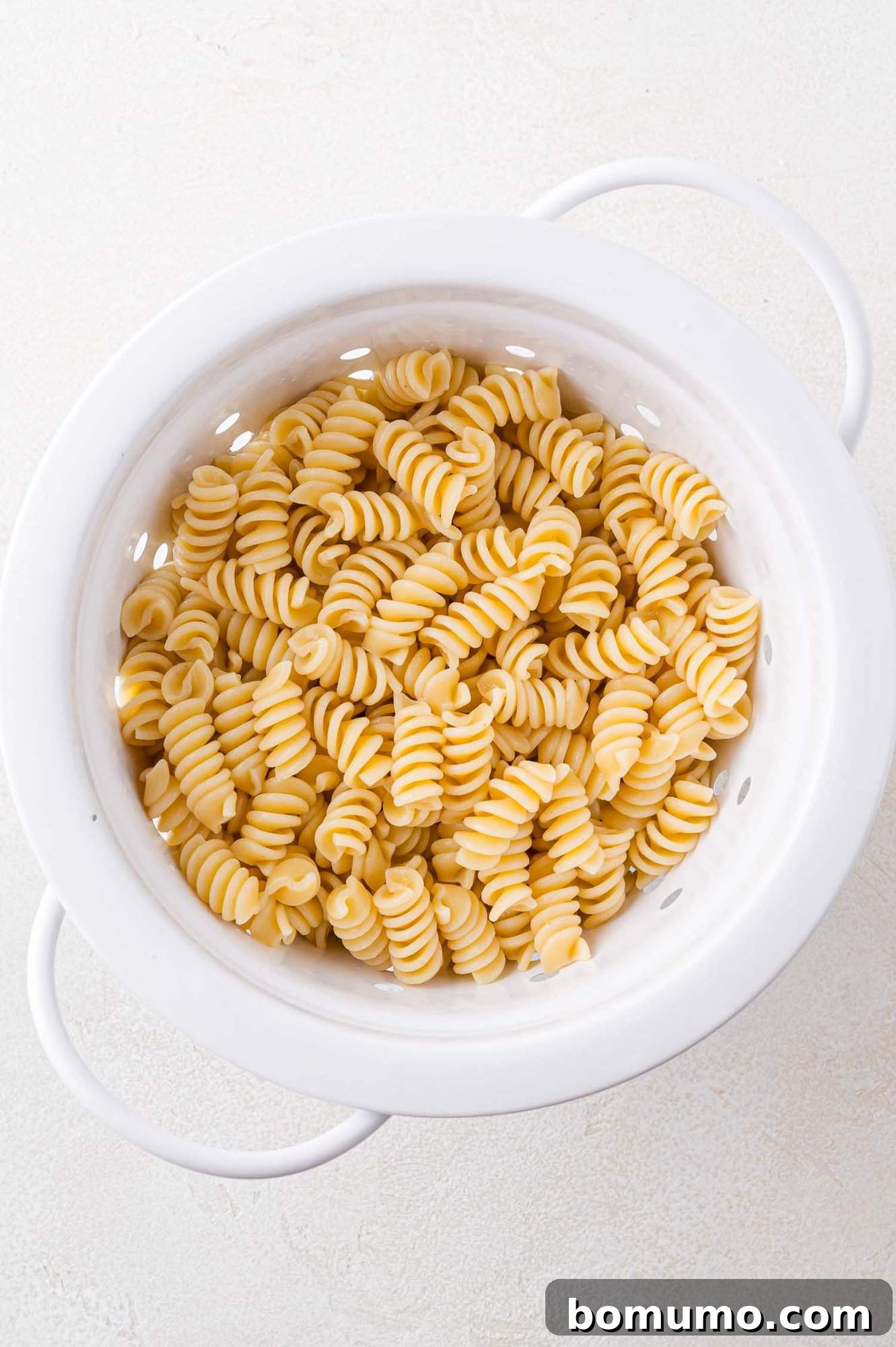 Cooked rotini pasta in a colander, freshly rinsed.