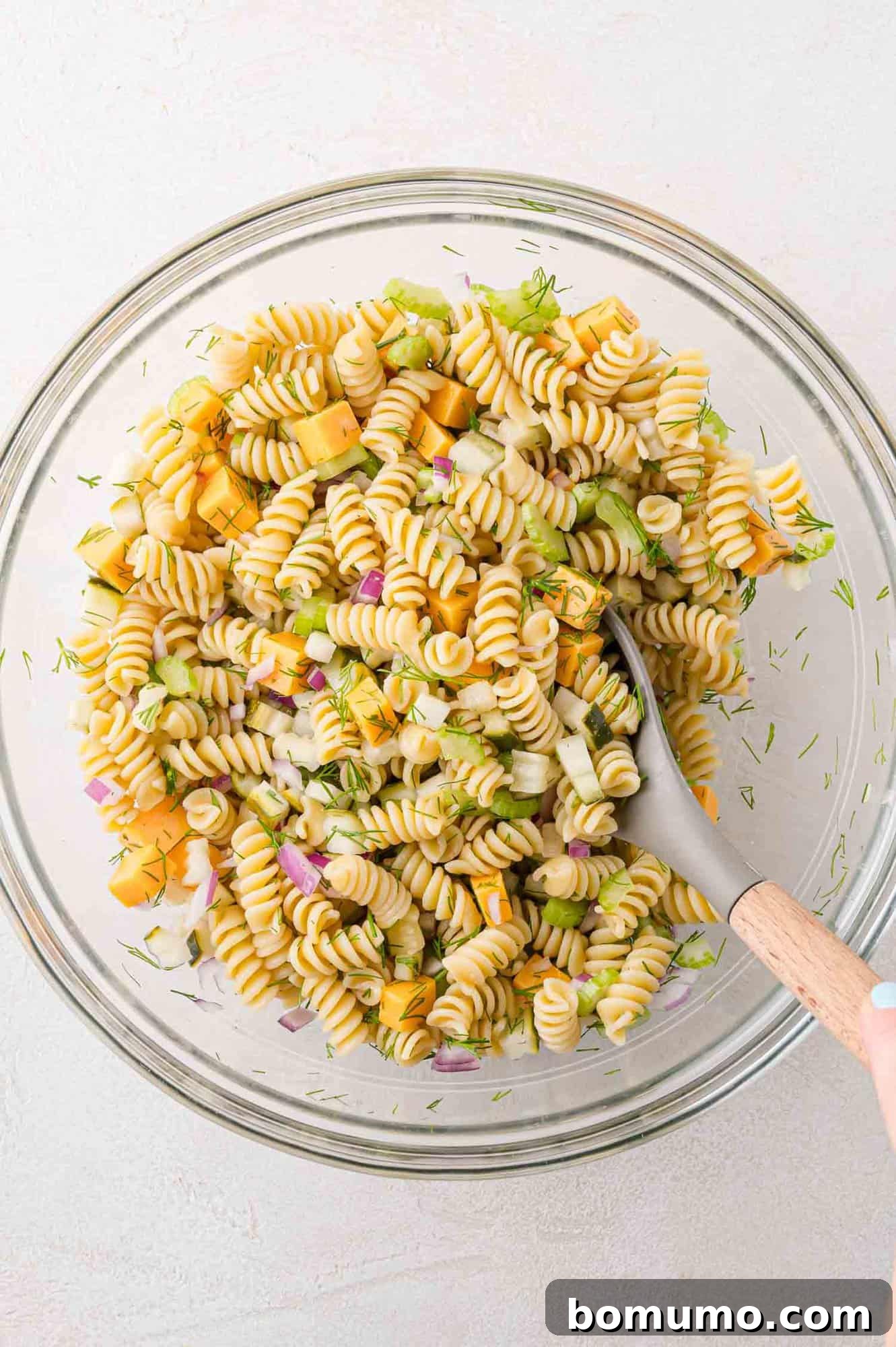 Pasta salad ingredients mixed together in a bowl, before dressing is added.