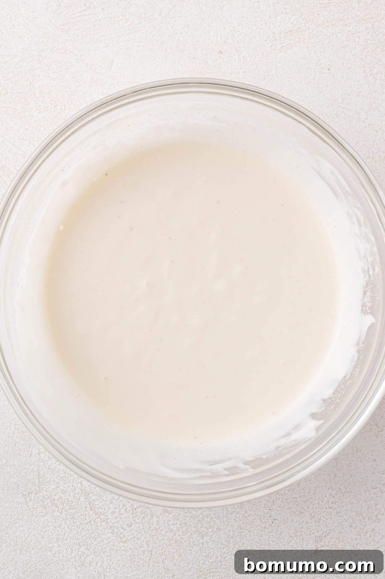 Dressing ingredients, combined and smooth in a clear glass bowl.