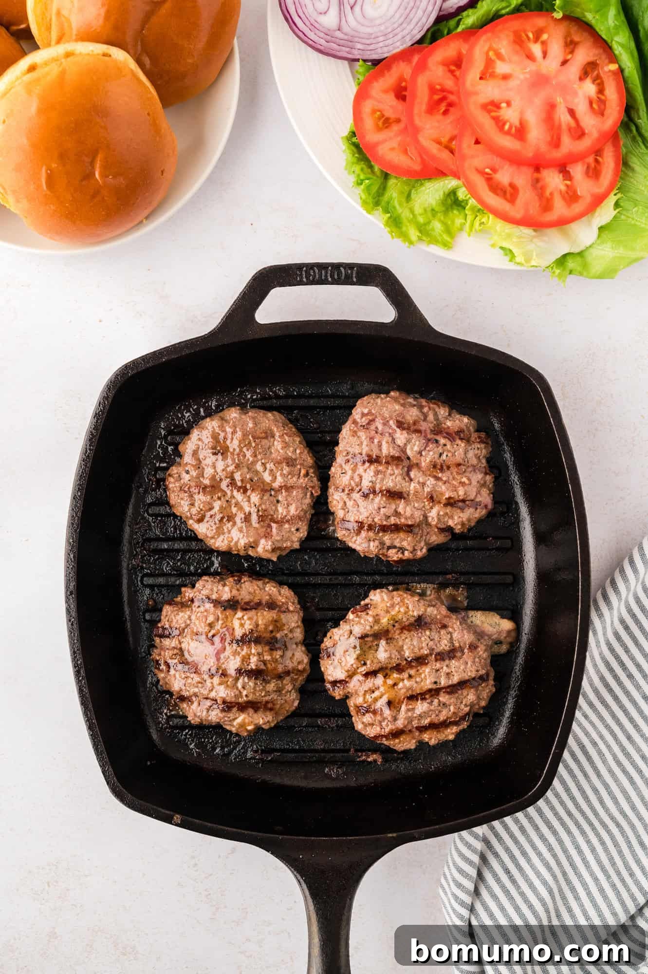 The Cali Dream Burger 11 Perfectly cooked burger patties resting on a grill pan, with a golden-brown crust.