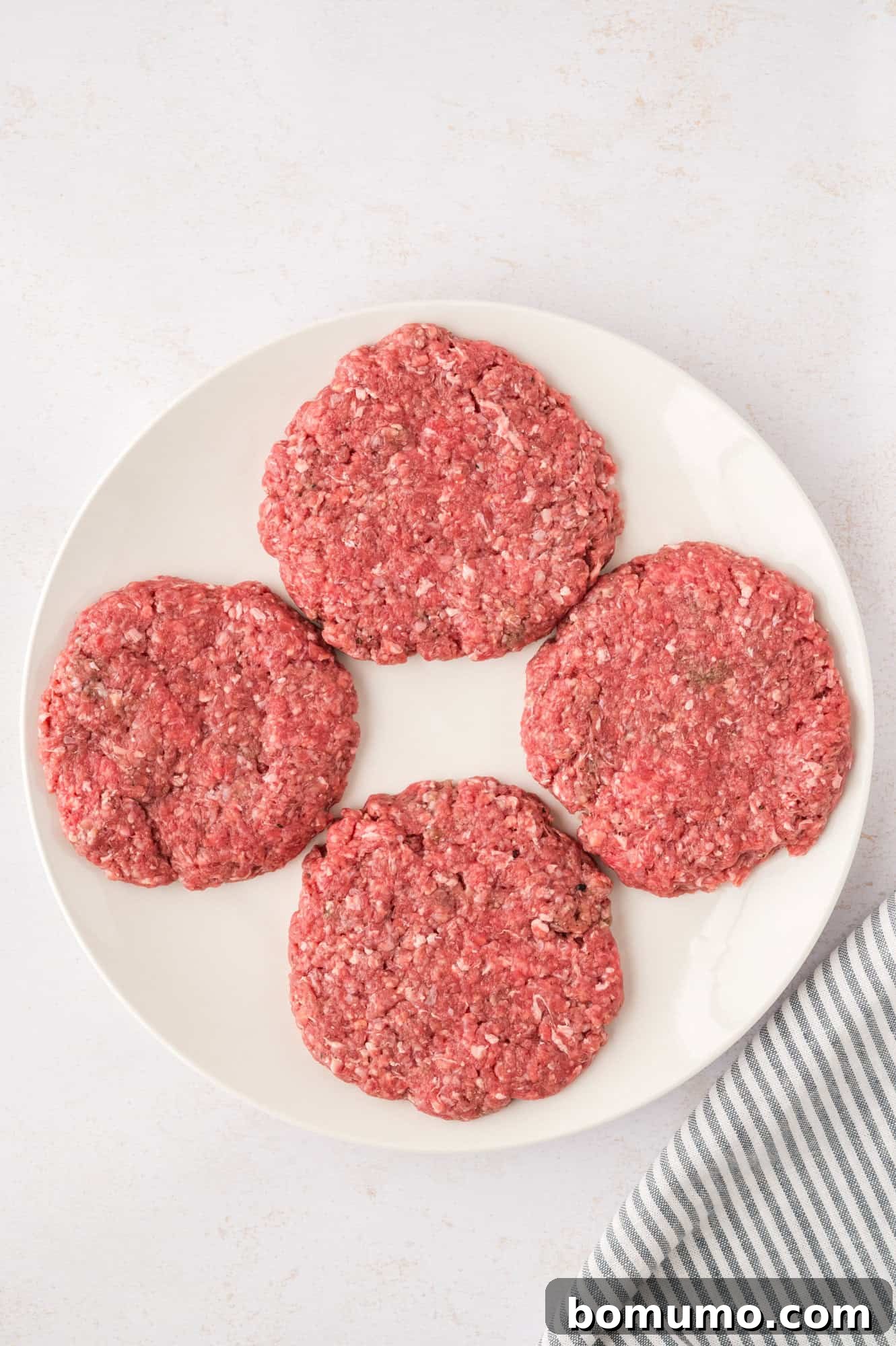 The Cali Dream Burger 9 Four uniform uncooked burger patties, prepared and ready for grilling.