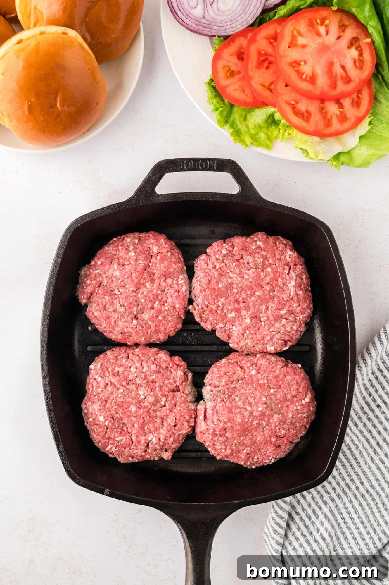 The Cali Dream Burger 10 Uncooked burger patties sizzling on a hot grill pan, showing early stages of cooking.