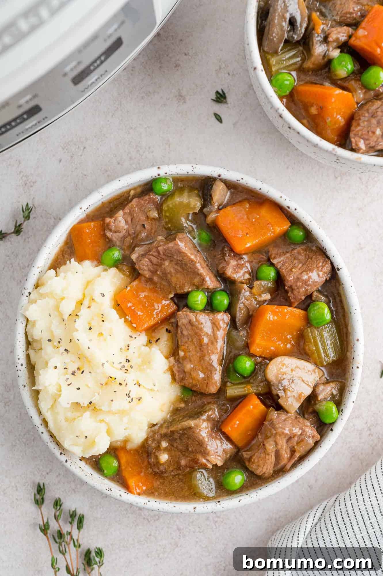 A hearty serving of Slow Cooker Beef Marsala Stew nestled over a generous scoop of creamy mashed potatoes, garnished for a perfect meal.