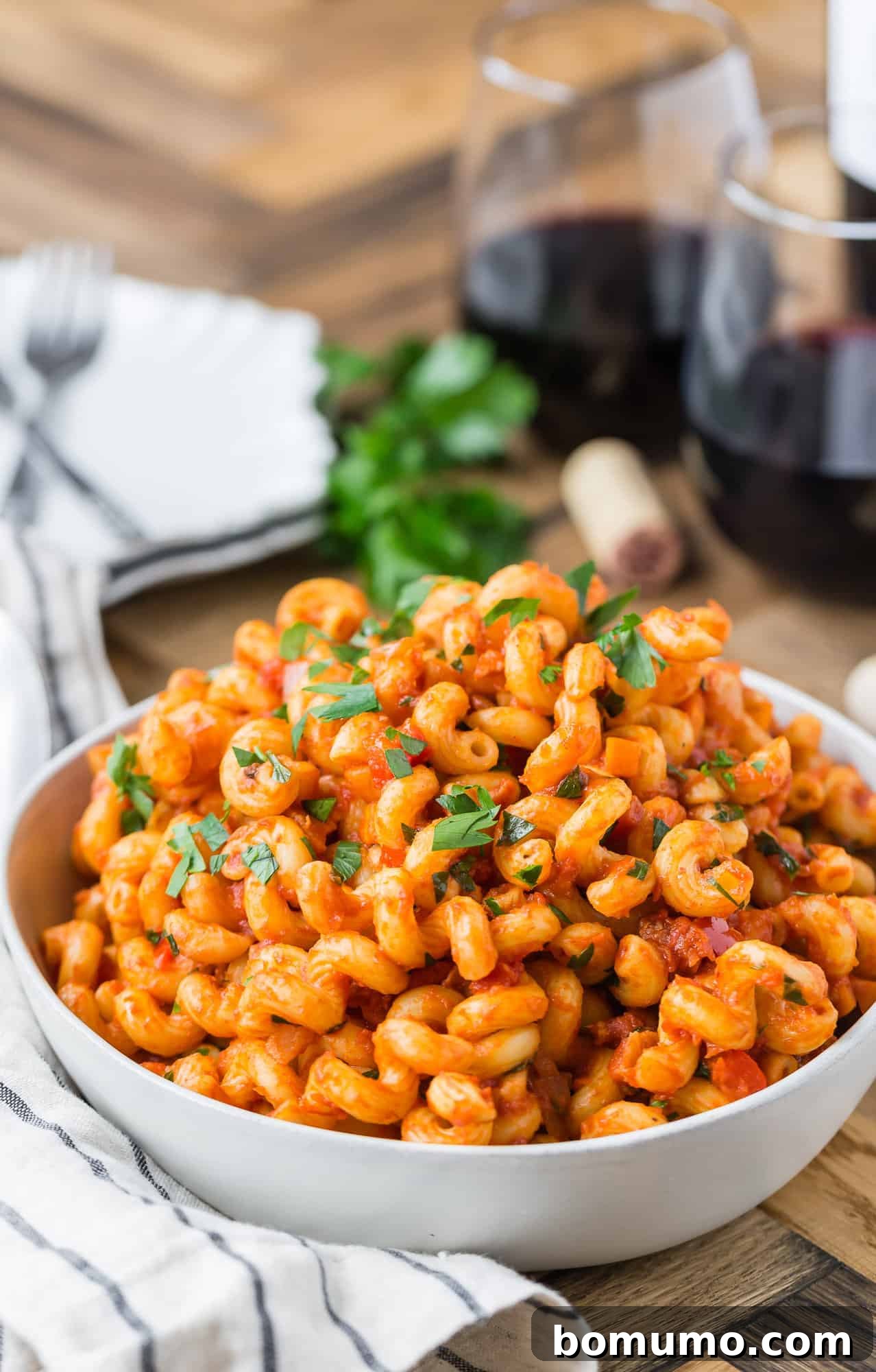 Pasta with crispy pancetta and a rich, smoky tomato sauce in a rustic bowl, garnished with fresh herbs.