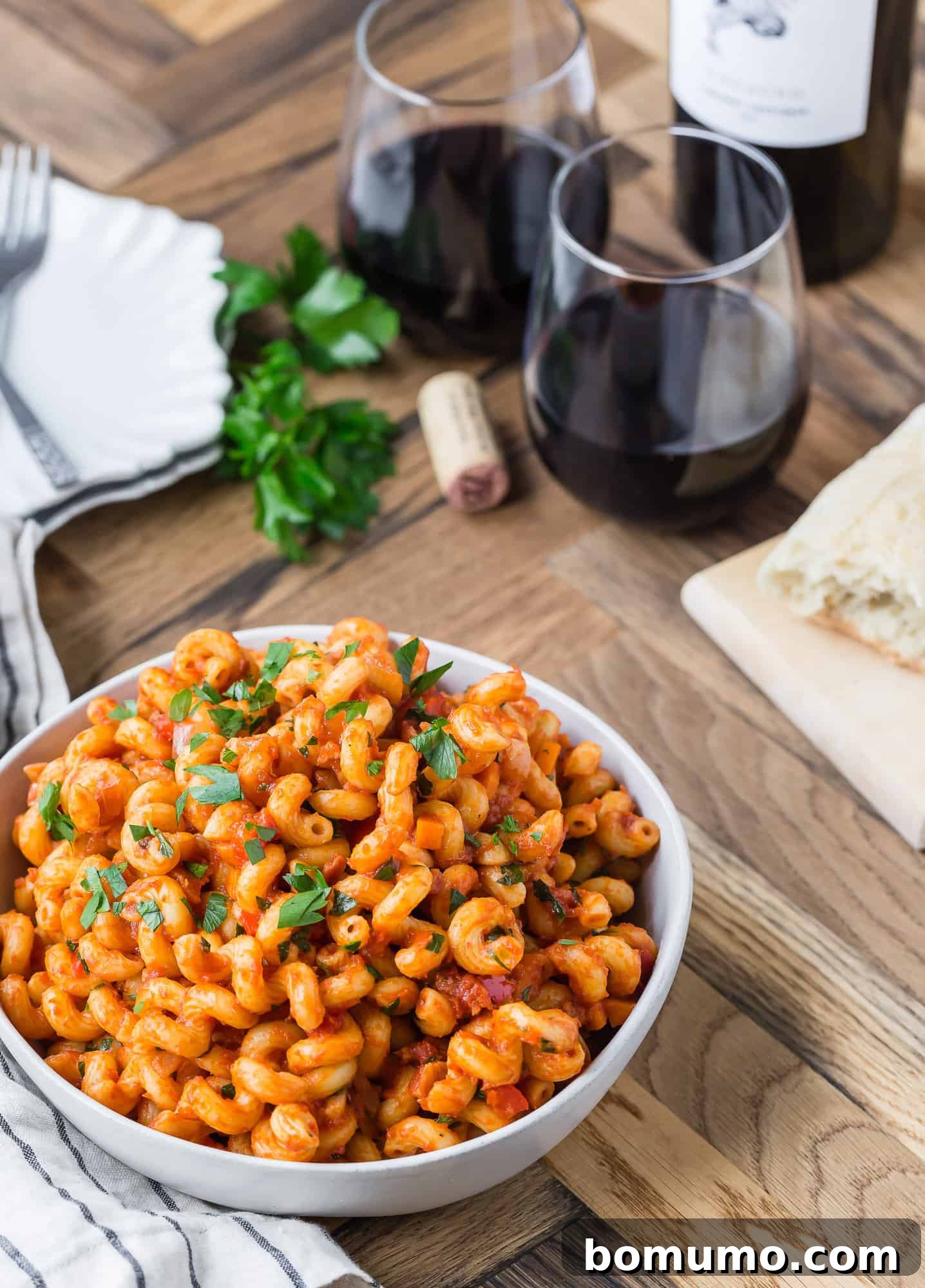 Close-up of pasta generously coated in a rich tomato sauce, served in a white bowl.