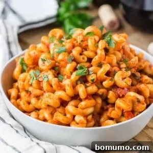 Pasta with pancetta and tomato sauce in white bowl.