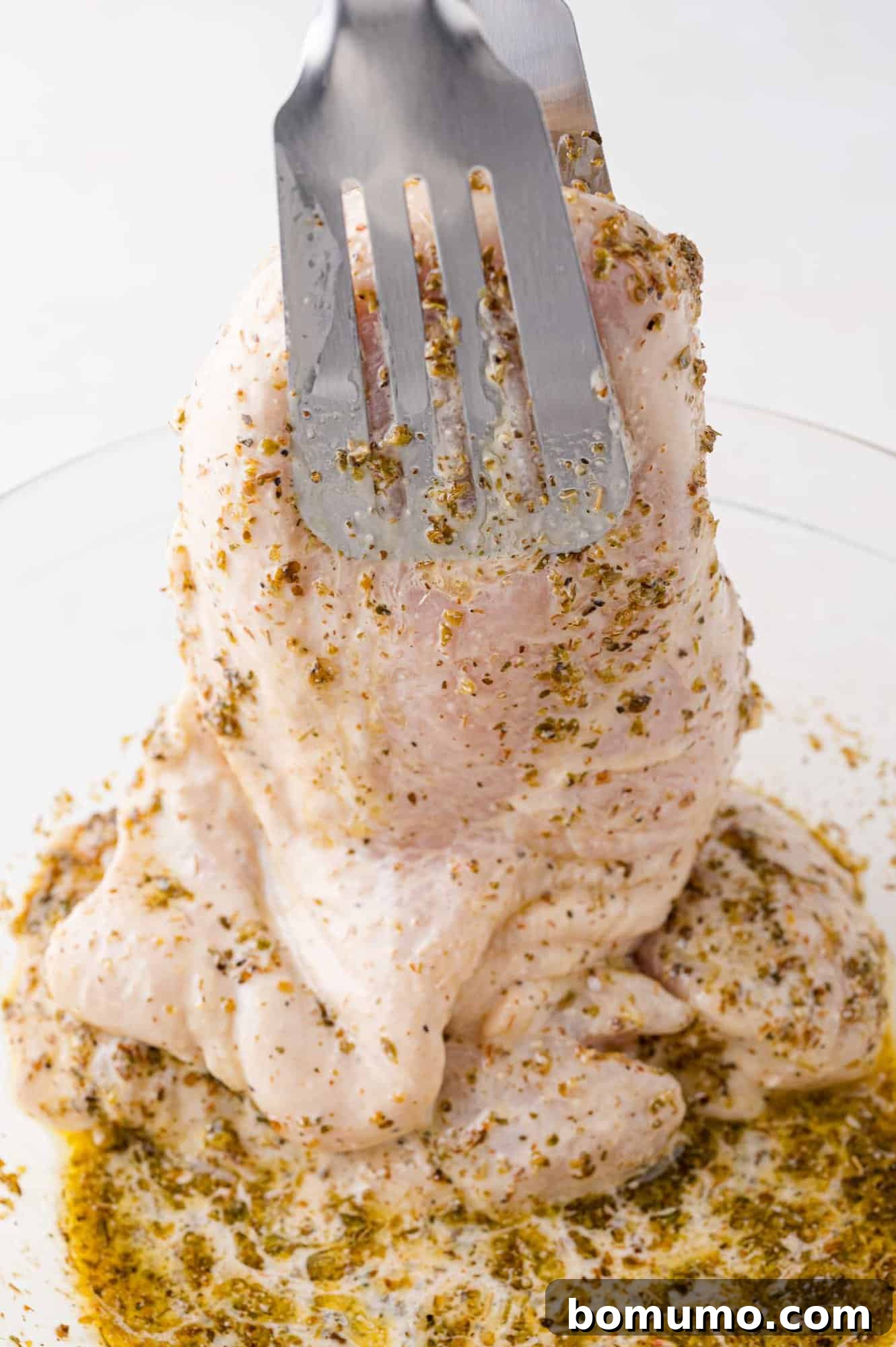 Chicken being removed from marinade, ready for cooking.