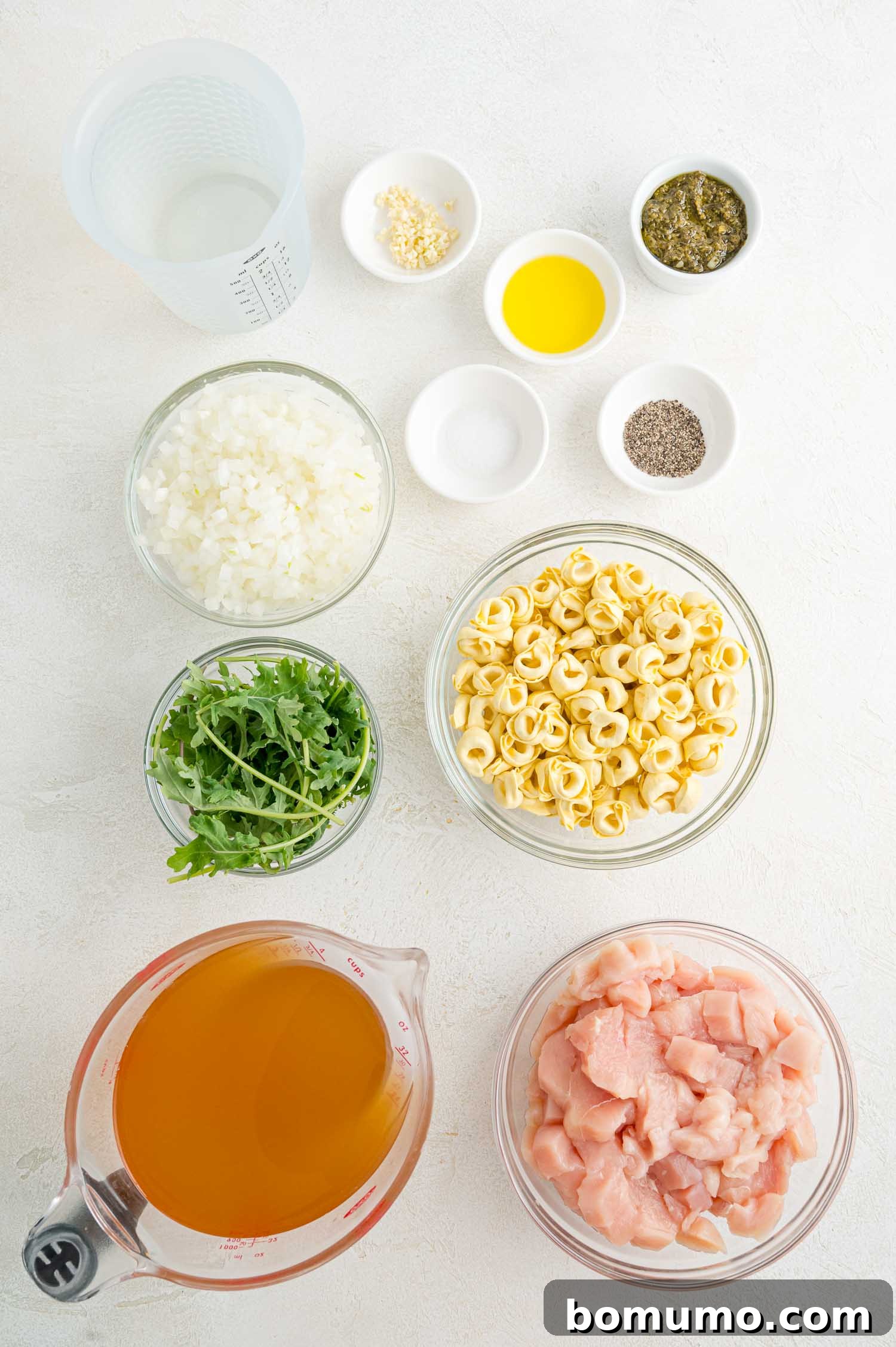 Various fresh ingredients for the chicken tortellini soup, neatly arranged in separate bowls, ready for preparation.