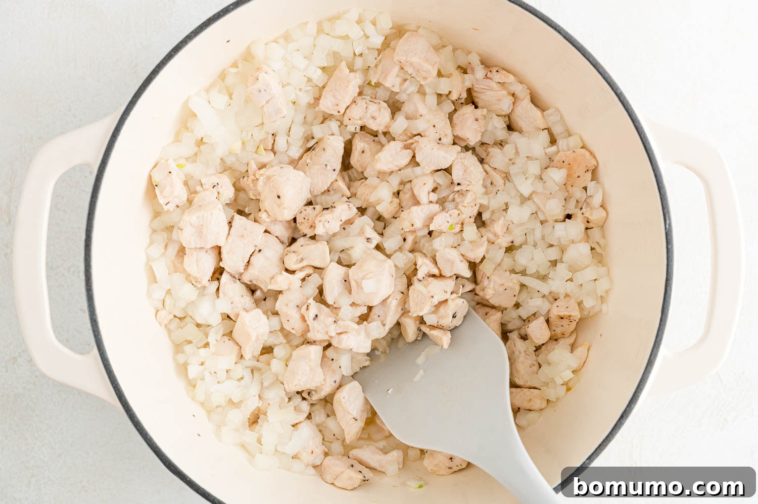 Chopped onions and minced garlic sizzling in the pan with the browned chicken, filling the air with enticing aromas.