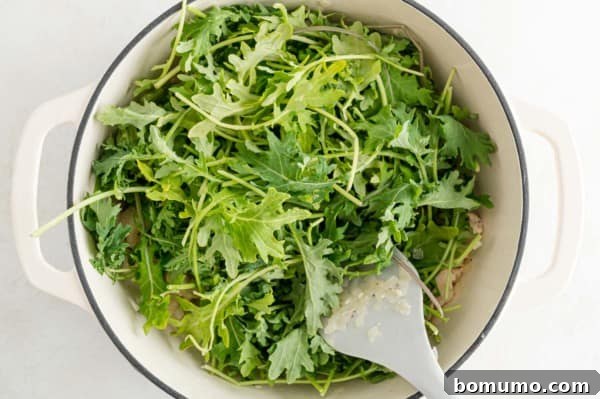A large pile of fresh baby kale leaves just added to the soup pot, looking voluminous before cooking.