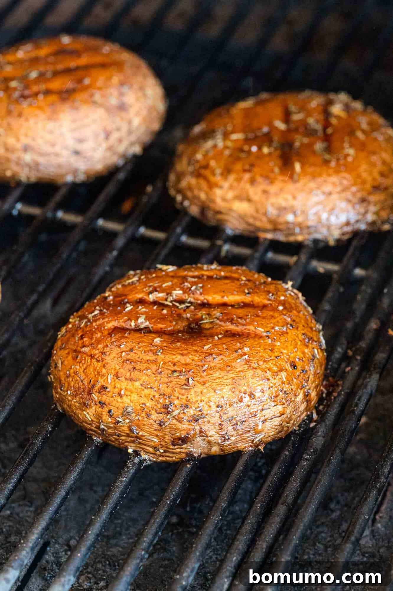 Portobello mushrooms cooking on a hot grill.