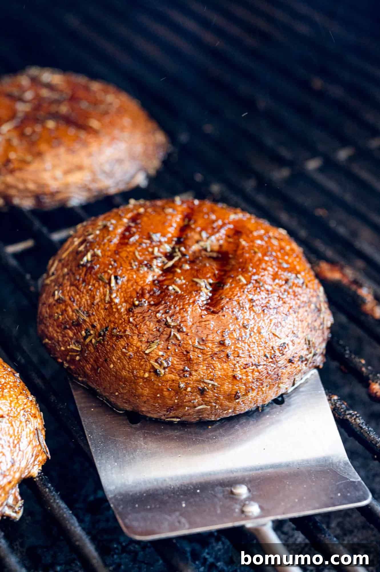 A perfectly grilled mushroom being removed from the grill.