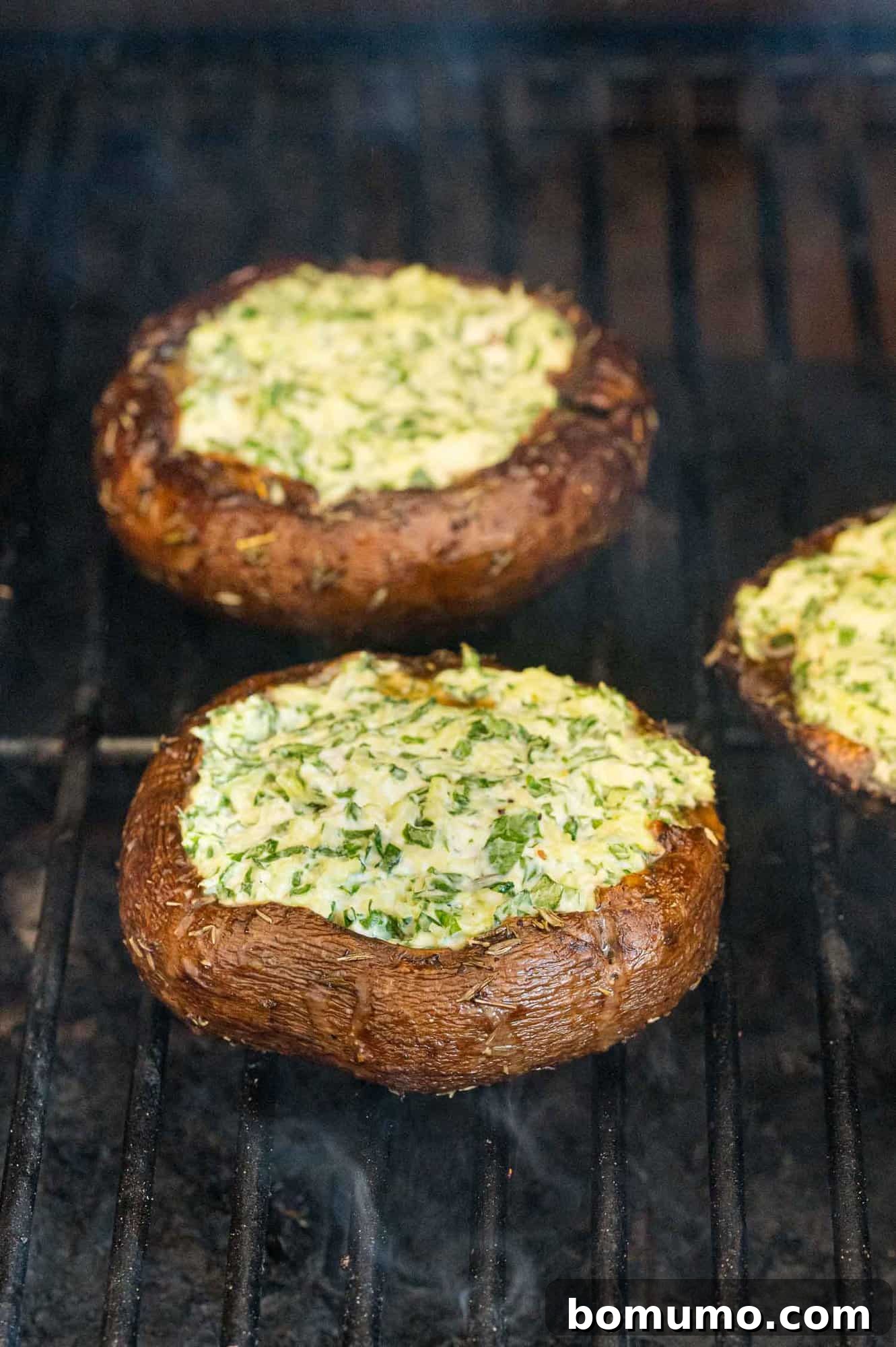 Stuffed portobello mushrooms grilling on an outdoor grill.