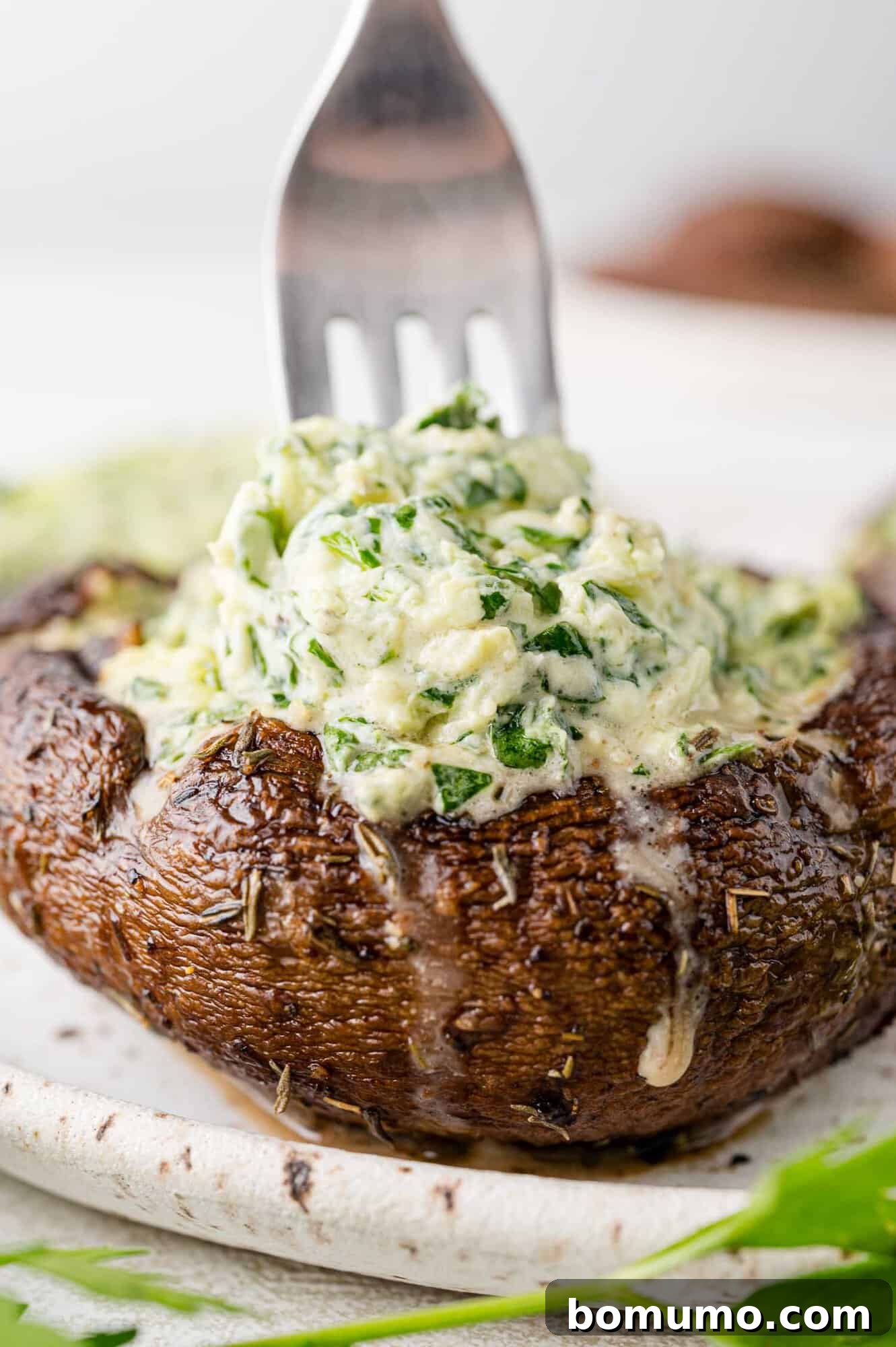 A fork piercing a perfectly cooked stuffed portobello mushroom.