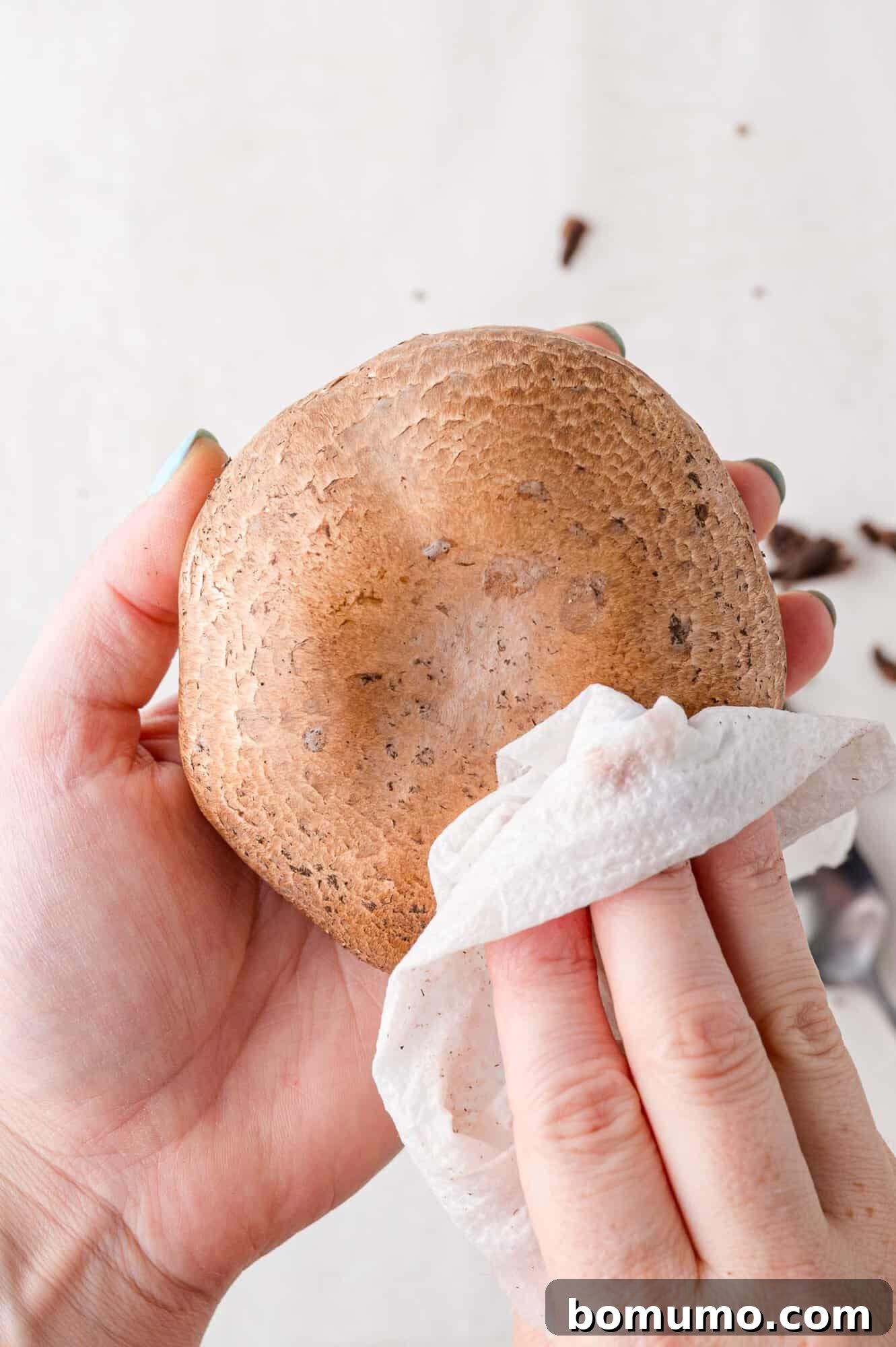 Mushroom cap being wiped clean with a cloth.