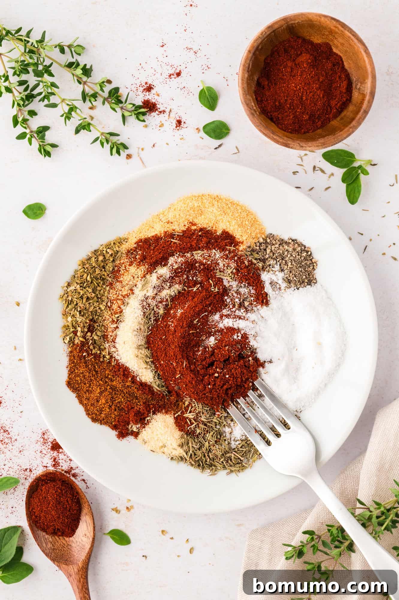 The initial stage of mixing spices for blackening seasoning, with a fork gently blending the ingredients within the bowl.