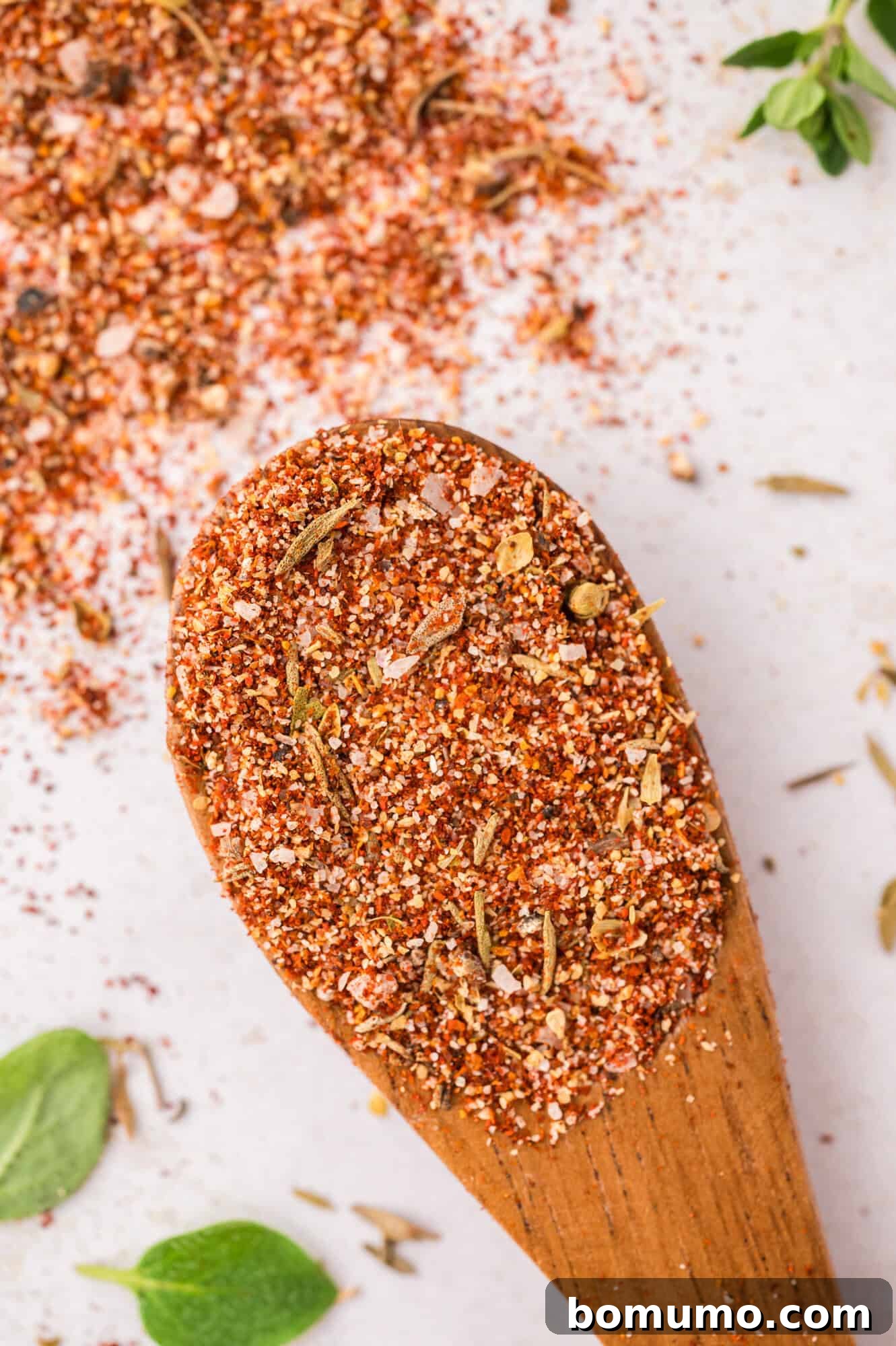 A close-up view of blackening seasoning resting on a small wooden spoon, highlighting its rich texture and color.