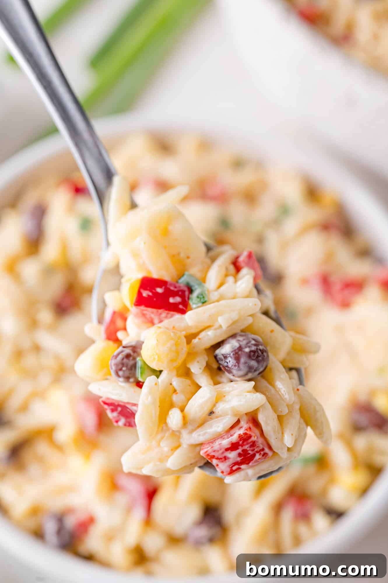 A small scoop of the creamy southwestern orzo salad presented on a serving spoon, ready for tasting.