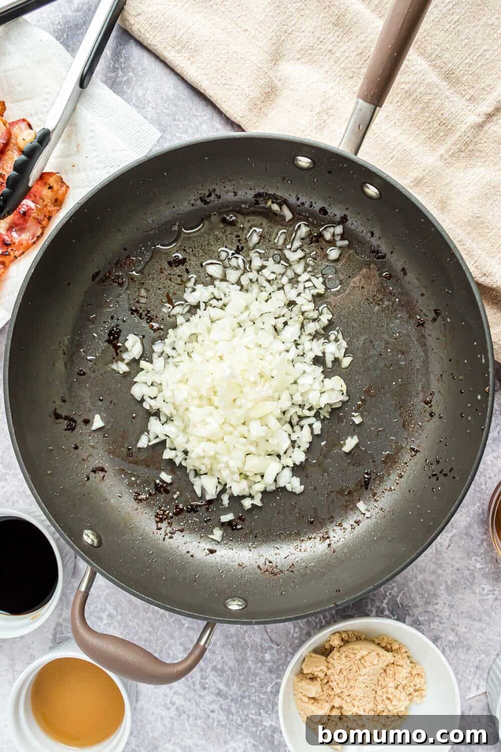 Sweet & Savory Bacon Jam 5 Finely diced Vidalia onions being added to the frying pan, glistening in the rendered bacon grease, ready to be slowly sautéed and caramelized.