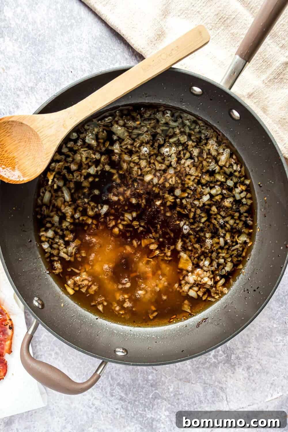 Sweet & Savory Bacon Jam 7 All the liquid ingredients - apple cider vinegar, maple bourbon, strong brewed coffee, balsamic vinegar, maple syrup, and brown sugar - have been added to the pan with the caramelized onions, creating a dark, rich mixture.