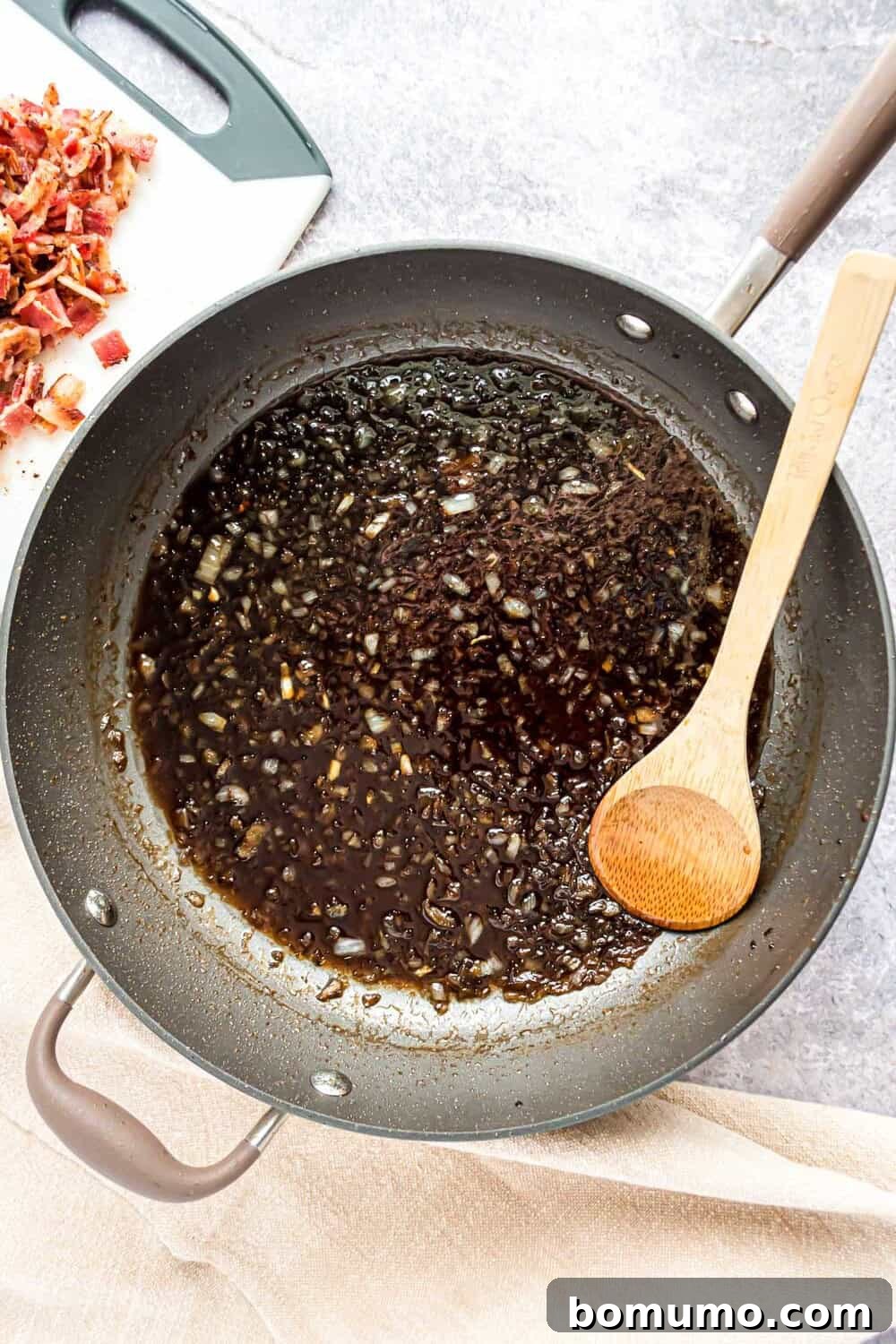 Sweet & Savory Bacon Jam 8 The liquid mixture with onions simmering gently in the skillet, having reduced and thickened slightly after 15 minutes of cooking, showcasing a deep, glossy appearance and melding flavors.