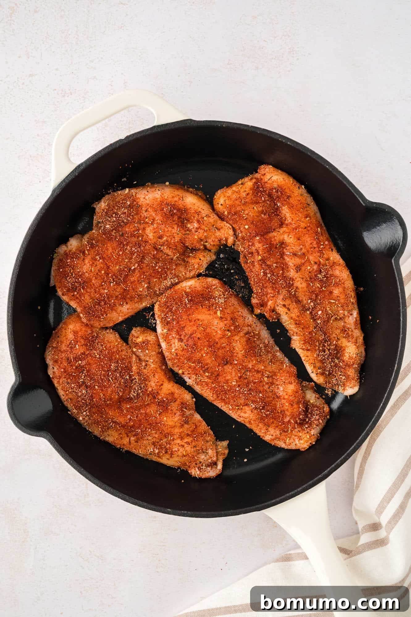 Spice rubbed chicken cutlets in a cast iron pan.
